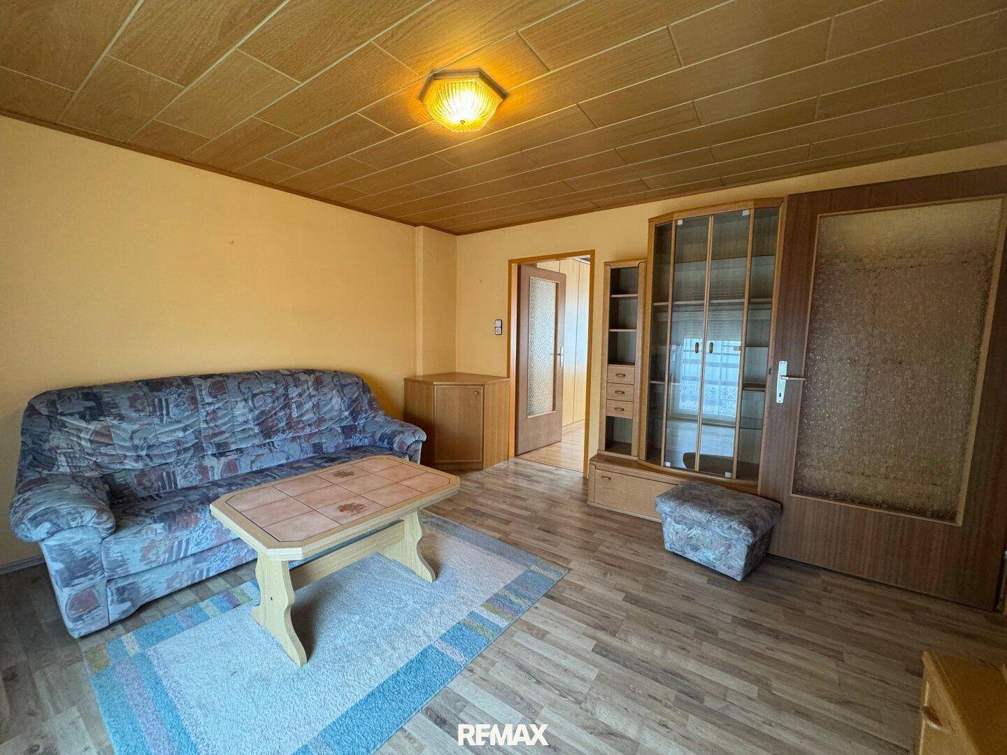 Gemütliches Wohnzimmer mit Holzdecke, Teppich und einem Sofa im traditionellen Stil.