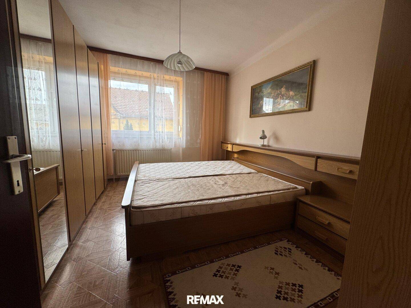 Schlafzimmer mit Doppelbett, Holzschränken und Blick ins Grüne.