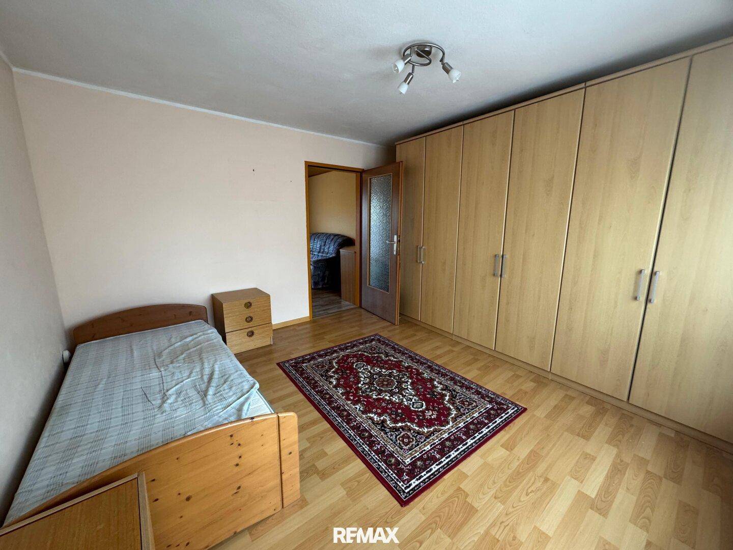 Helles Schlafzimmer mit Laminatboden, Einbauschränken und Einzelbett.
