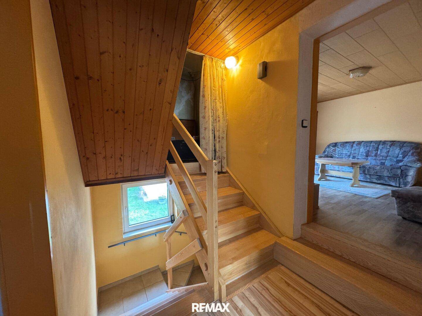 Holztreppe führt in den oberen Bereich, mit Blick auf den Wohnbereich.