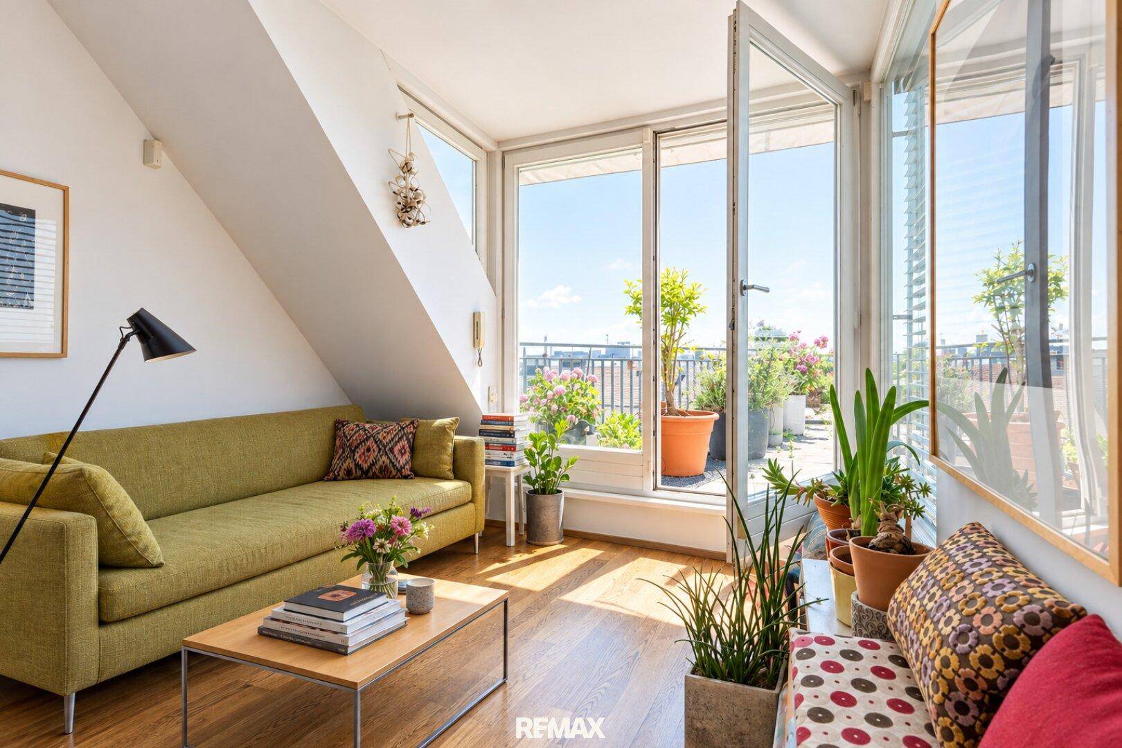 Helles Wohnzimmer mit Zugang zu einer Dachterrasse, Holzboden und vielen Pflanzen.