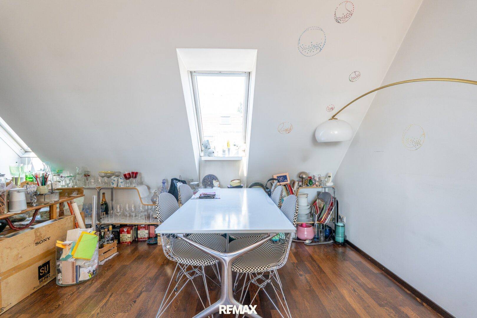 Essbereich im Dachgeschoss mit großem Esstisch, Designstühlen und Dachfenster.