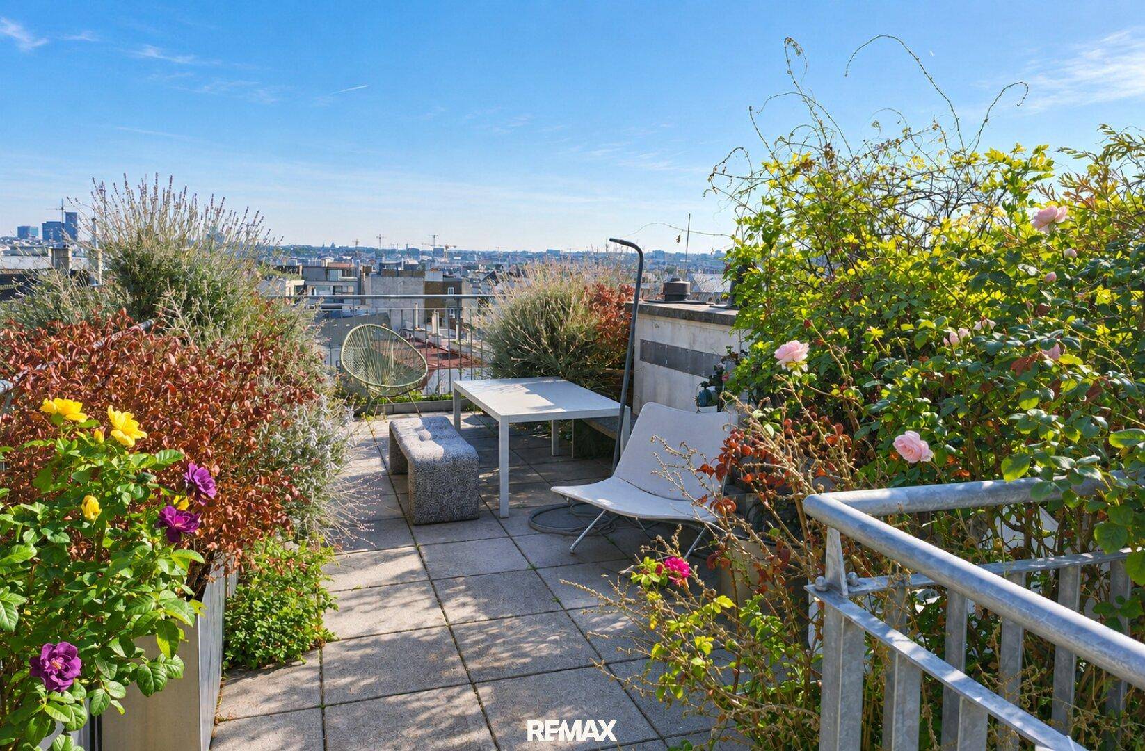 Weitläufige Dachterrasse mit Sitzgelegenheiten, üppiger Bepflanzung und Stadtblick.