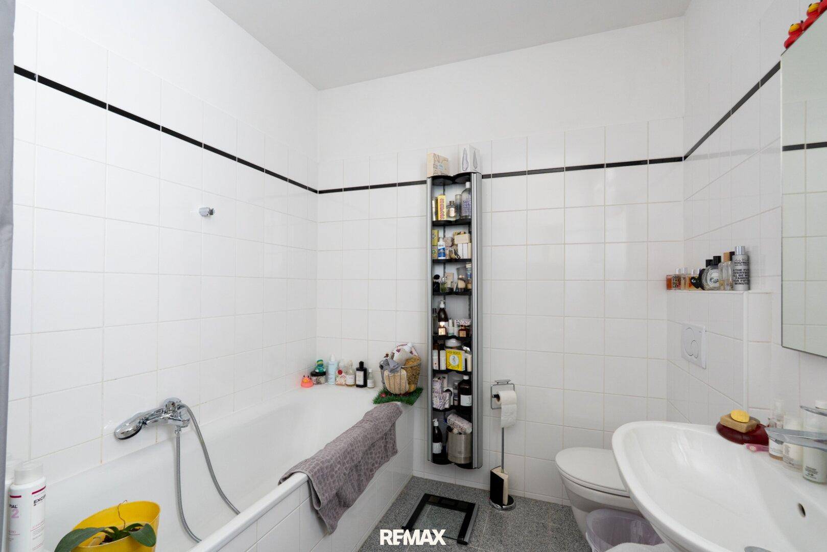 Funktionales Badezimmer mit Badewanne, WC, Waschbecken und weißen Fliesen.