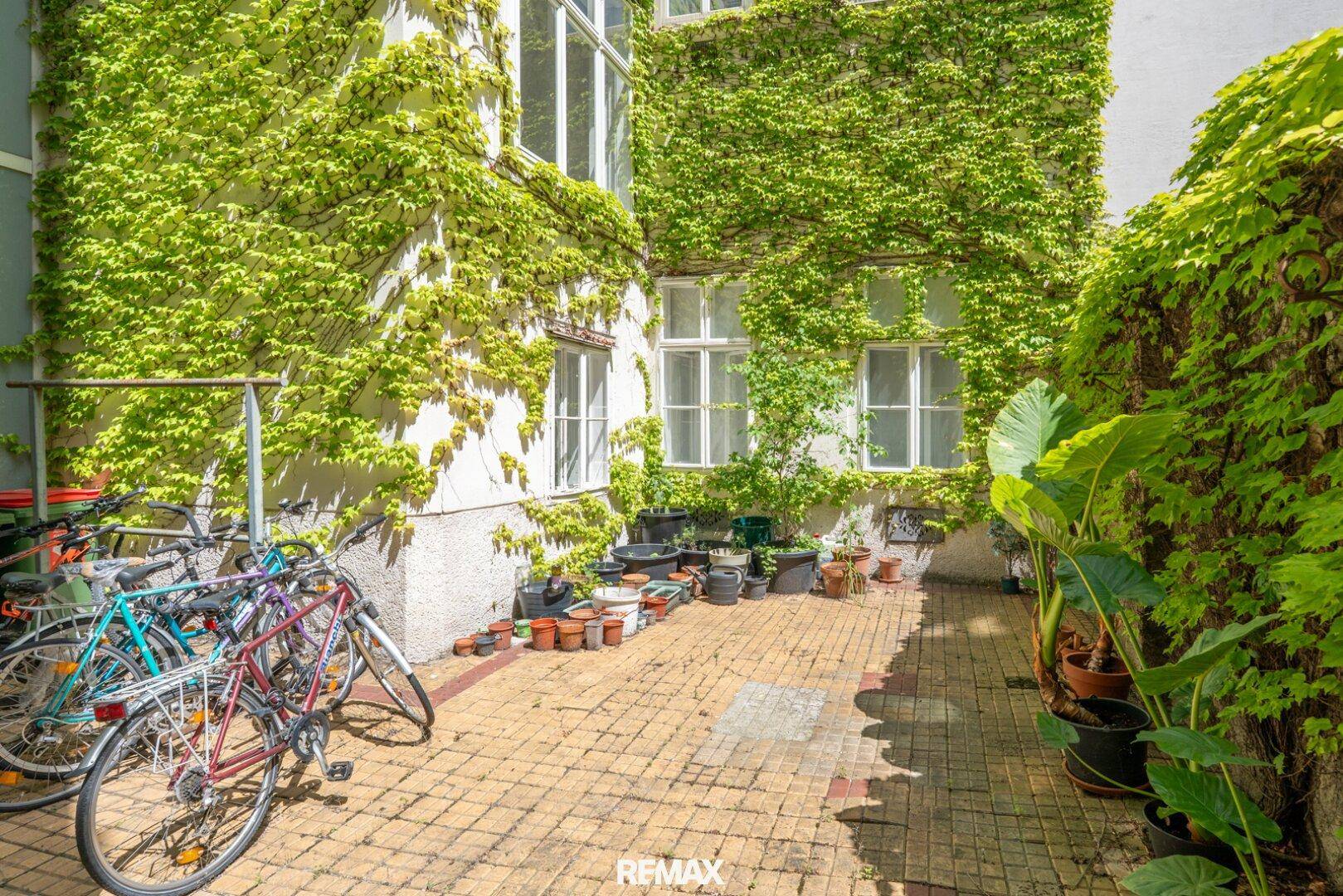 Begrünter Innenhof mit Kletterpflanzen an der Fassade und Fahrradabstellmöglichkeiten.