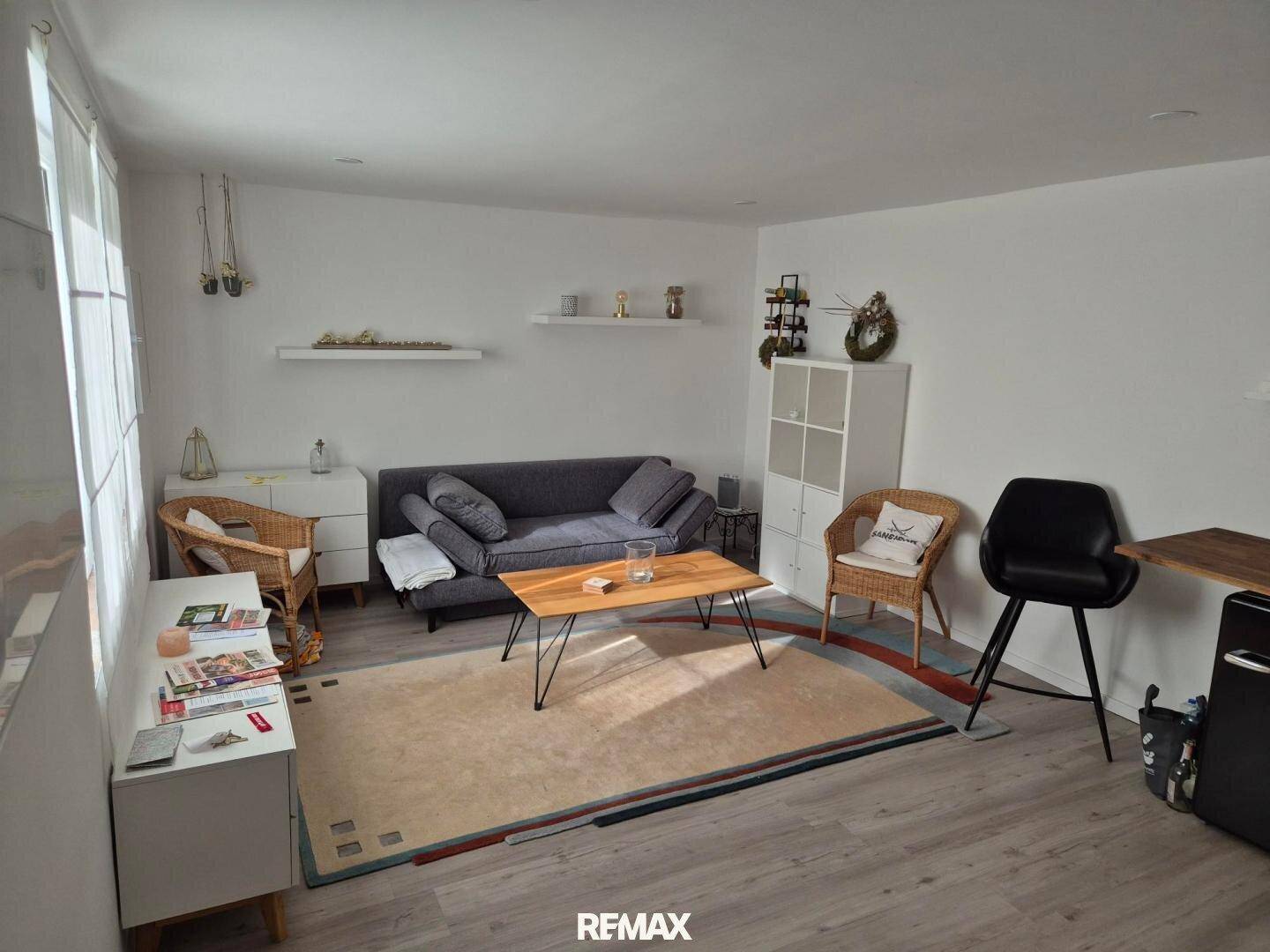 Helles Wohnzimmer mit modernem Sofa, Couchtisch und hellem Laminatboden.