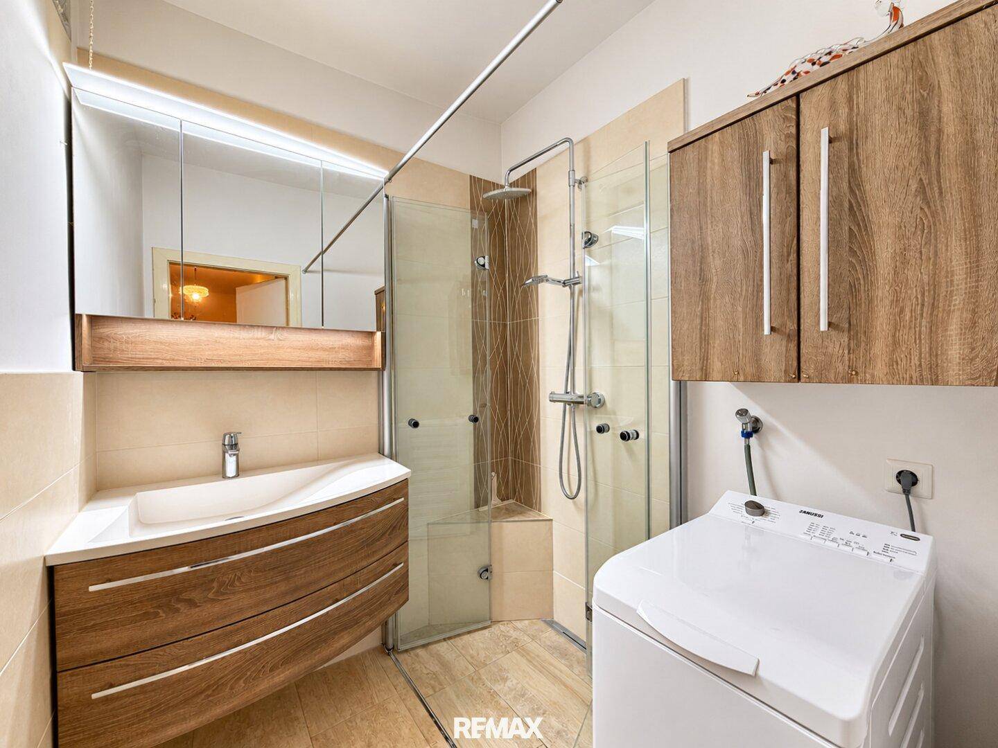 Modernes Badezimmer mit begehbarer Dusche, stilvollem Waschtisch und Waschmaschine.