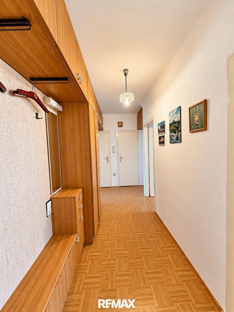 Langer Flur mit integrierten Holzschränken und dekorativen Bildern an der Wand.