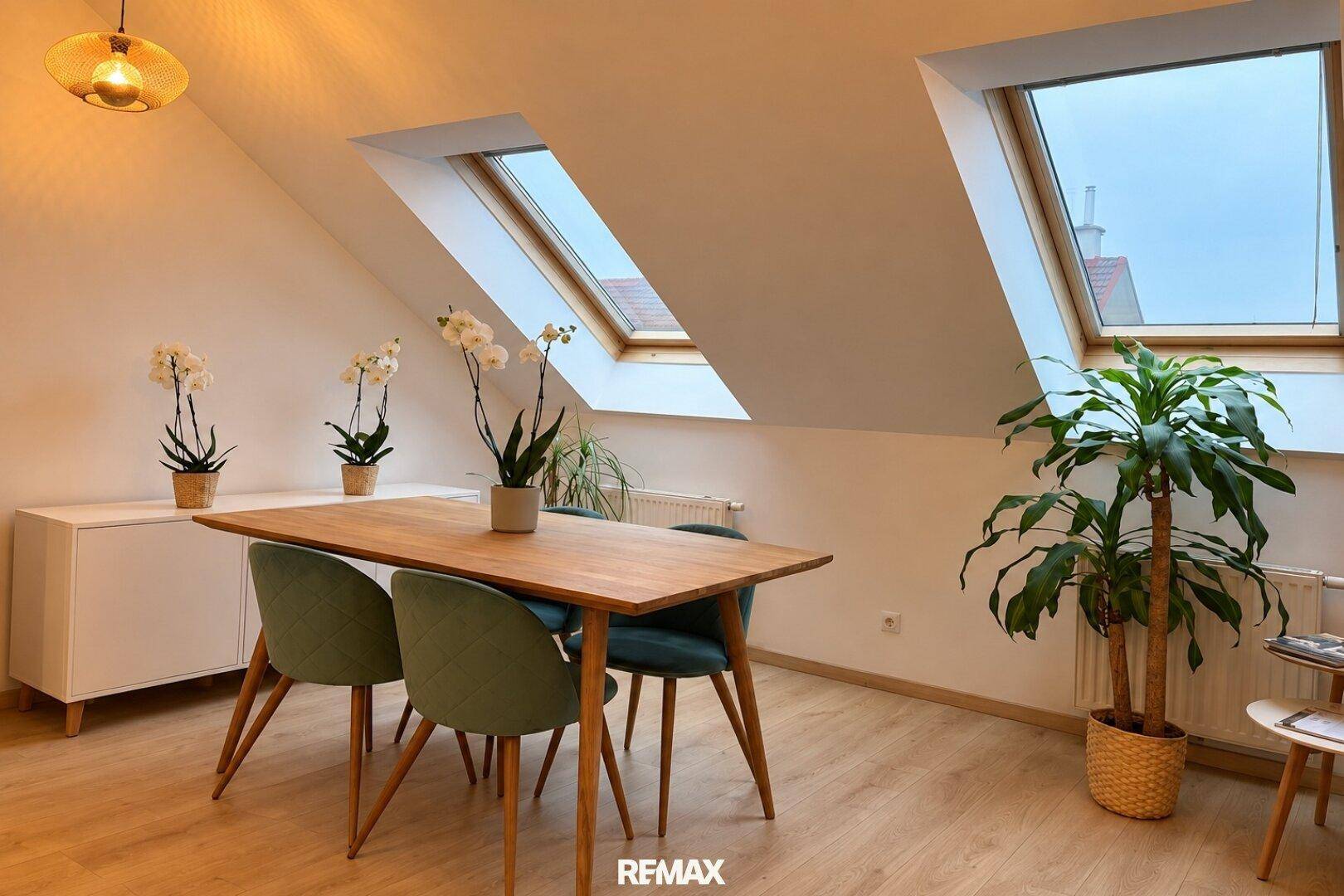 Heller Essbereich im Dachgeschoss mit Holztisch, modernen Stühlen und großen Dachfenstern.
