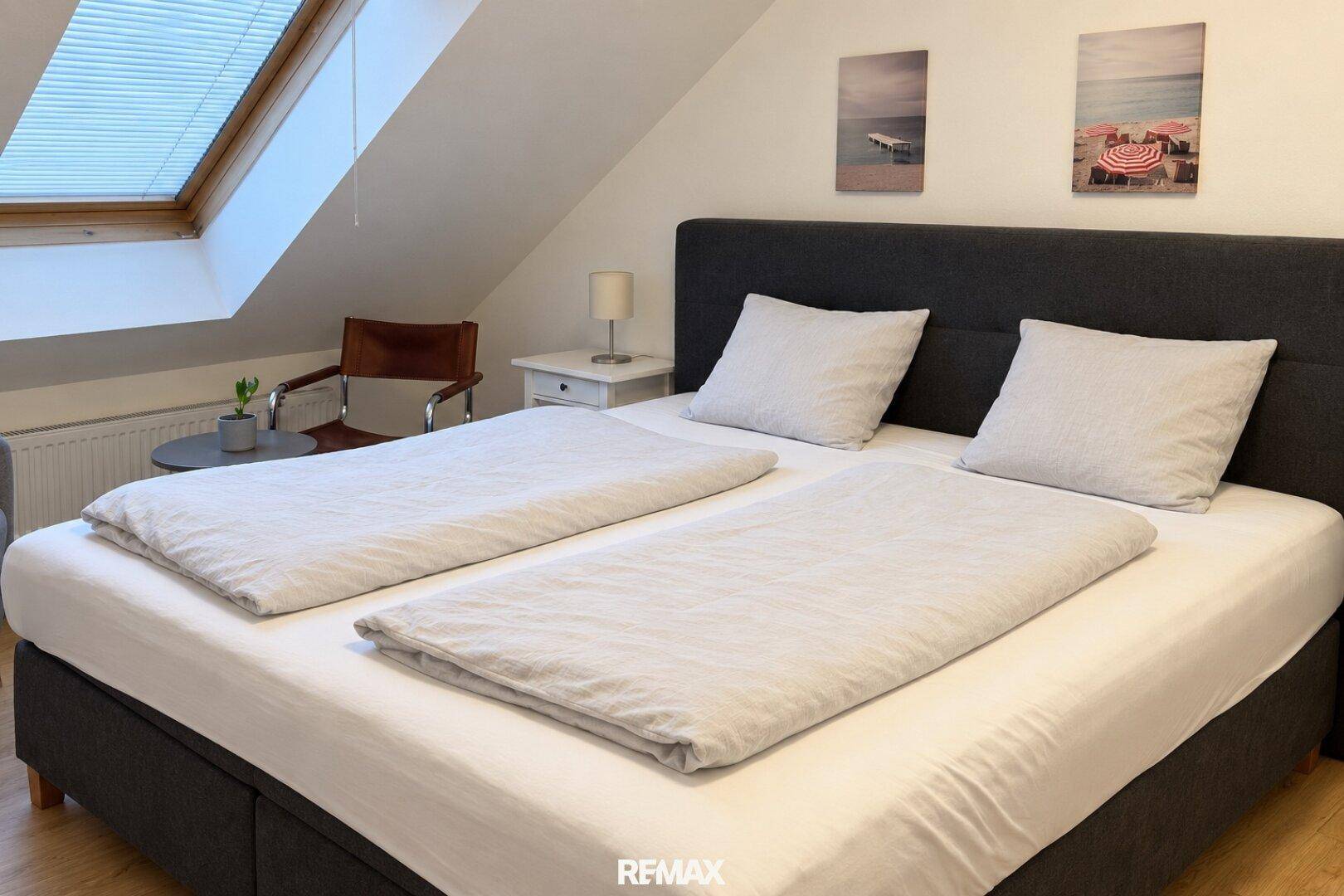 Schlafzimmer im Dachgeschoss mit Doppelbett, Nachttisch und einem großen Dachfenster.