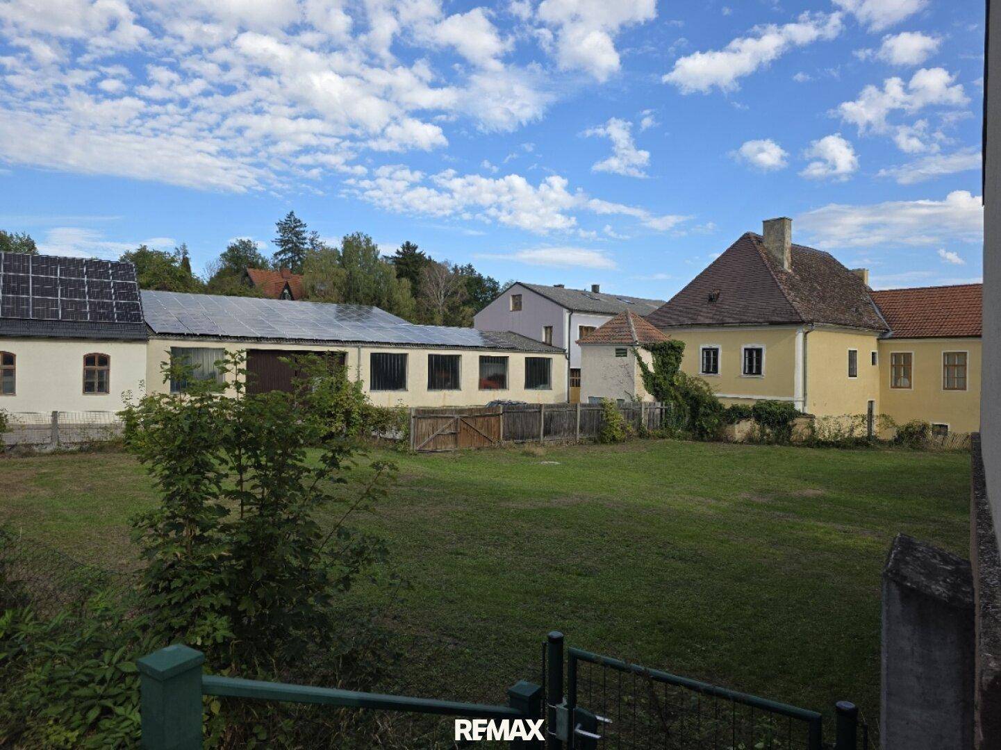 Blick über eine weitläufige Rasenfläche auf mehrere Gebäude, teilweise mit Solaranlagen auf den Dächern.