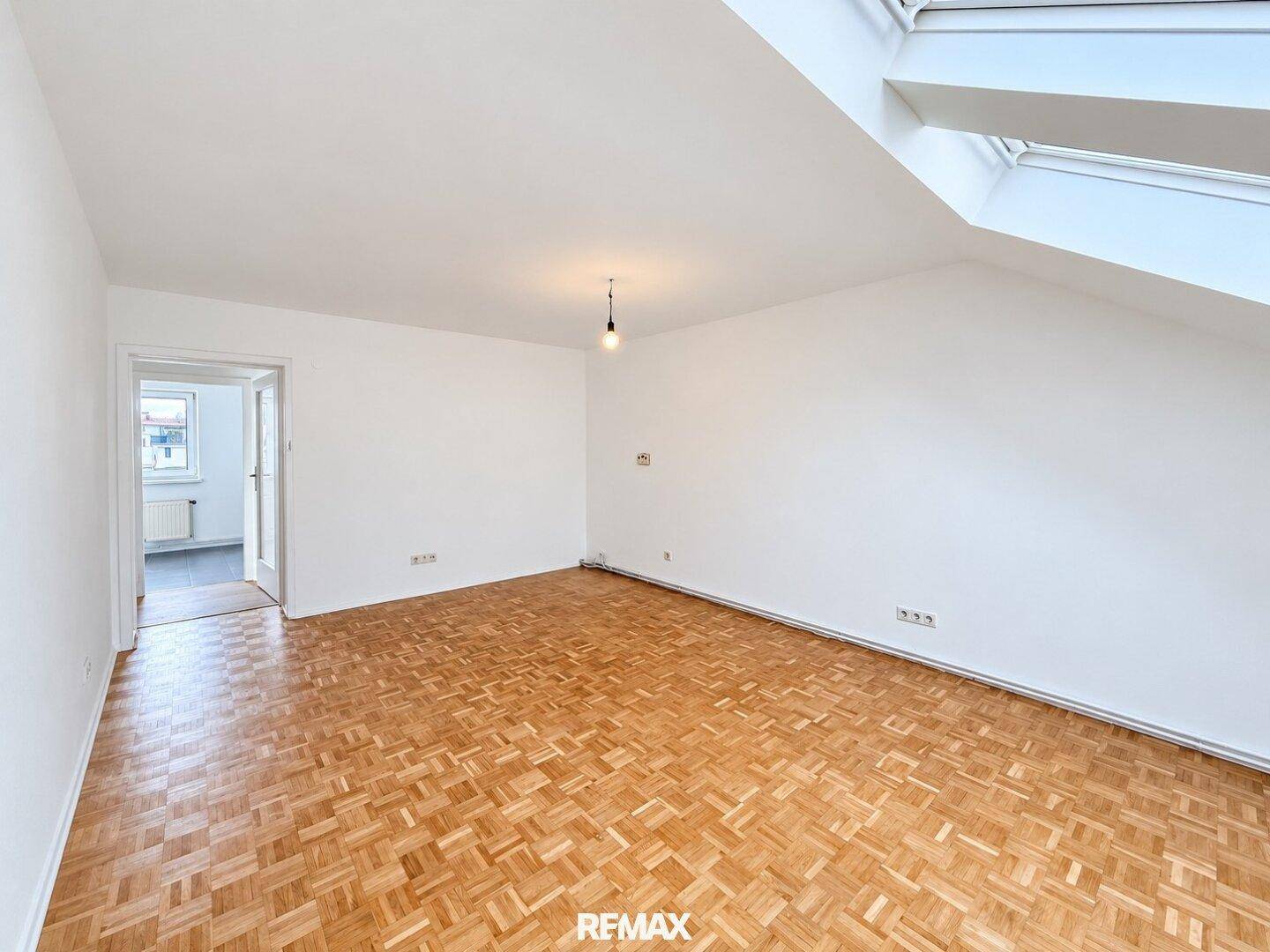 Geräumiges Zimmer mit Parkettboden, weißen Wänden und einem großen Dachfenster für viel Licht.