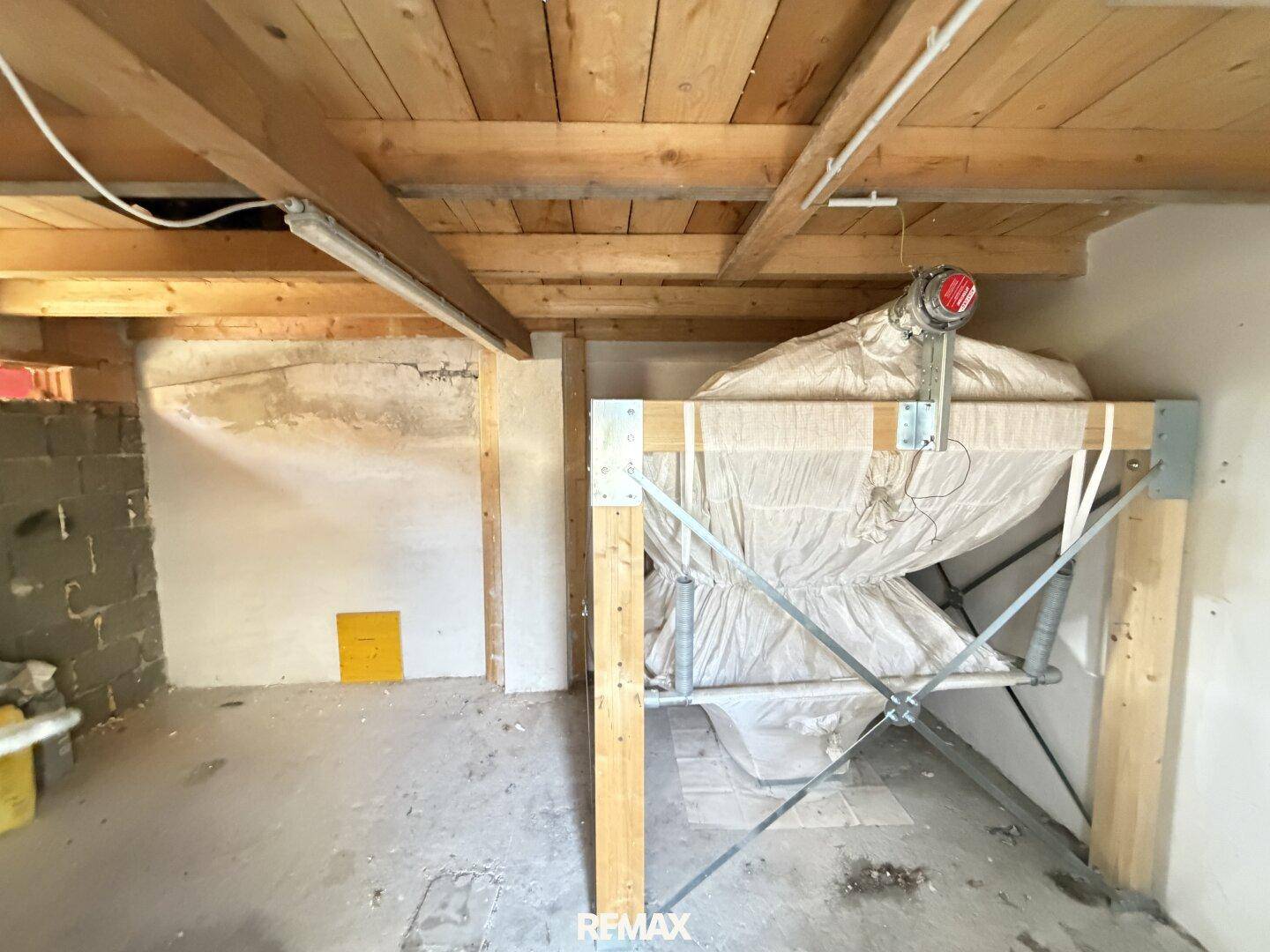 Kellerraum mit sichtbaren Holzbalken und einem großen Lagerbehälter, ideal für Stauraum.