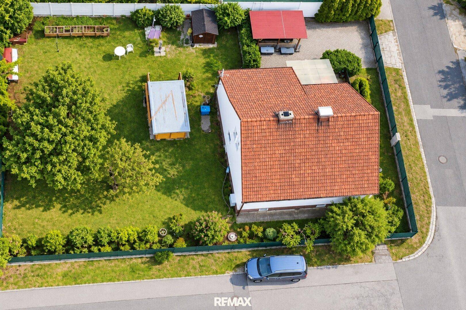 Dachansicht des Einfamilienhauses mit rotem Ziegeldach und weitläufigem grünen Gartenbereich.