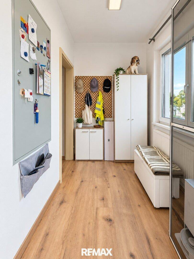 Heller Eingangsbereich mit Holzboden, Sitzbank und praktischen Aufbewahrungsmöbeln.