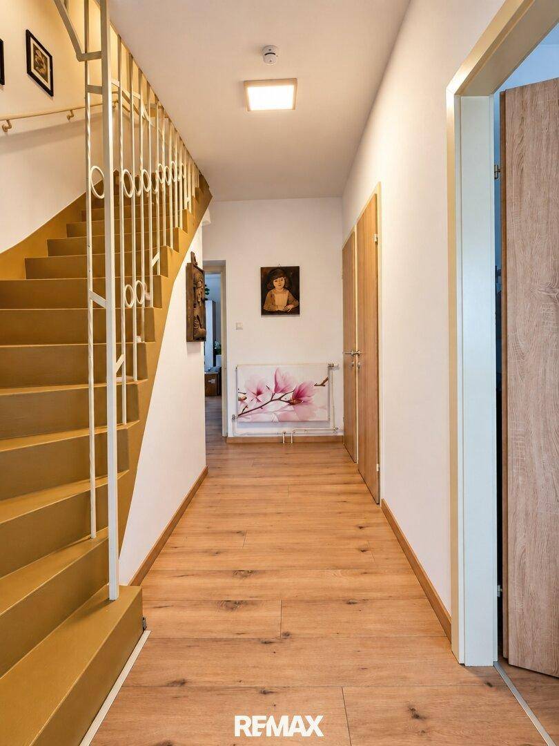 Geräumiger Flur mit Holztreppe und hellem Holzboden, der zu den oberen Etagen führt.