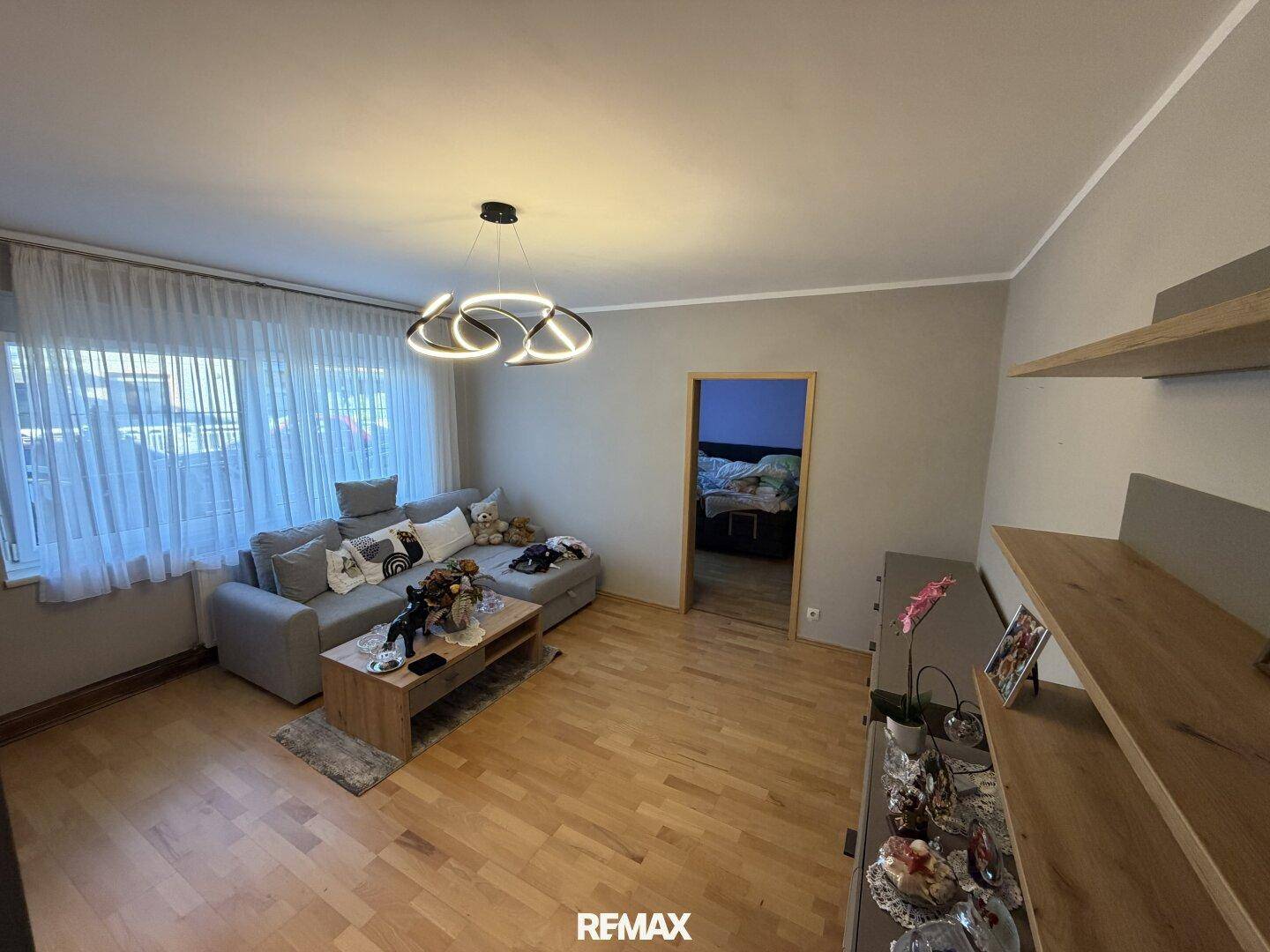 Helles Wohnzimmer mit großem Sofa, Holzboden und dekorativen Regalen.