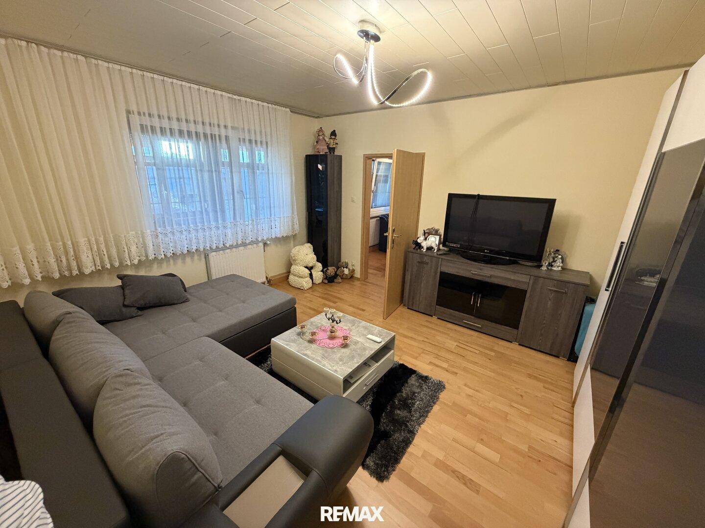 Gemütliches Wohnzimmer mit großem Ecksofa, Holzboden und Deckenpaneelen.