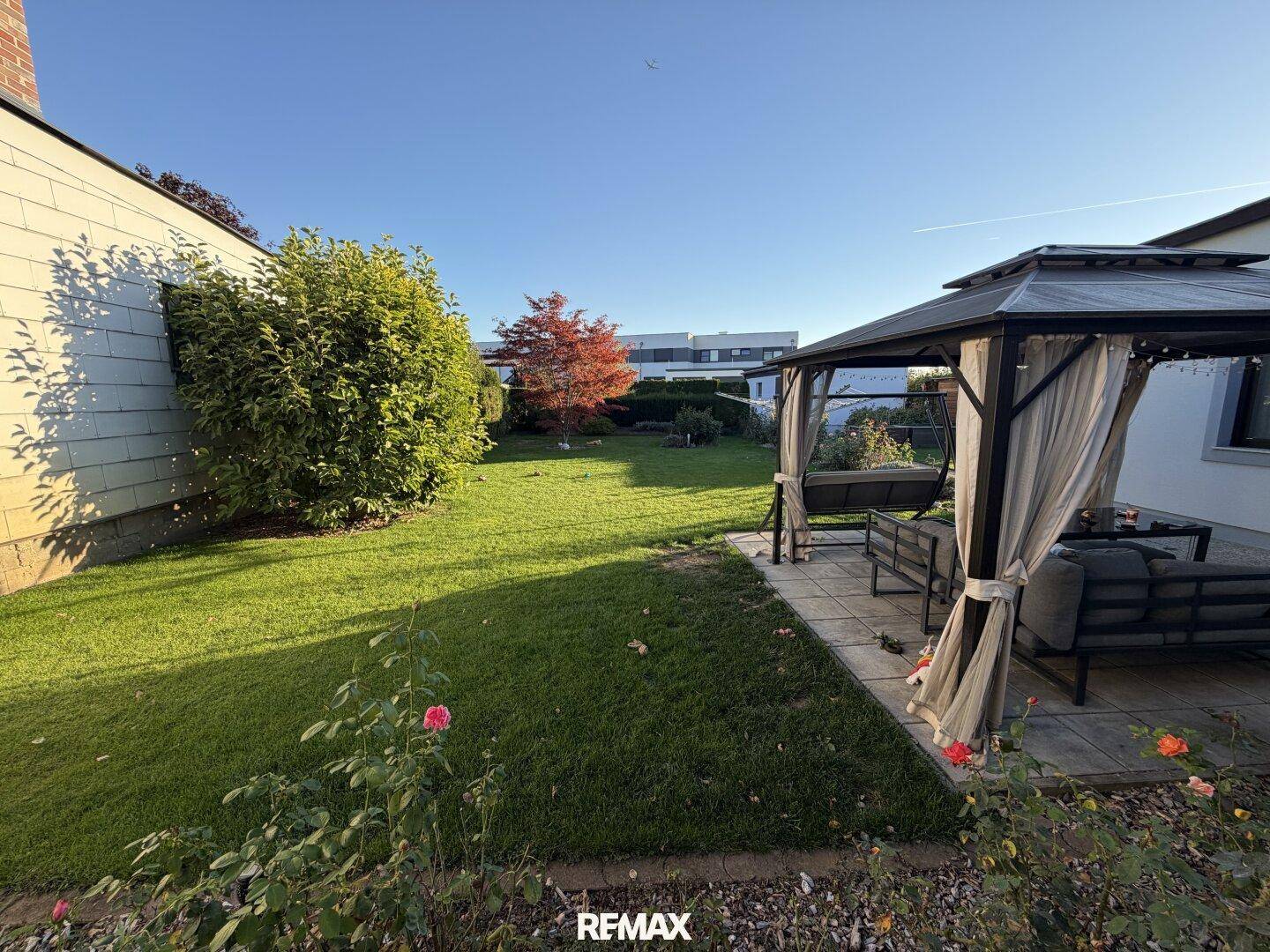 Sonniger Garten mit Pavillon und Rasenfläche, ideal für Entspannung im Freien.