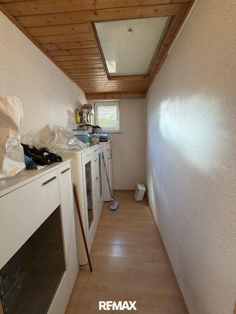 Schmaler Abstellraum mit Schränken, Holzboden und Holzdecke, ideal für Lagerung.