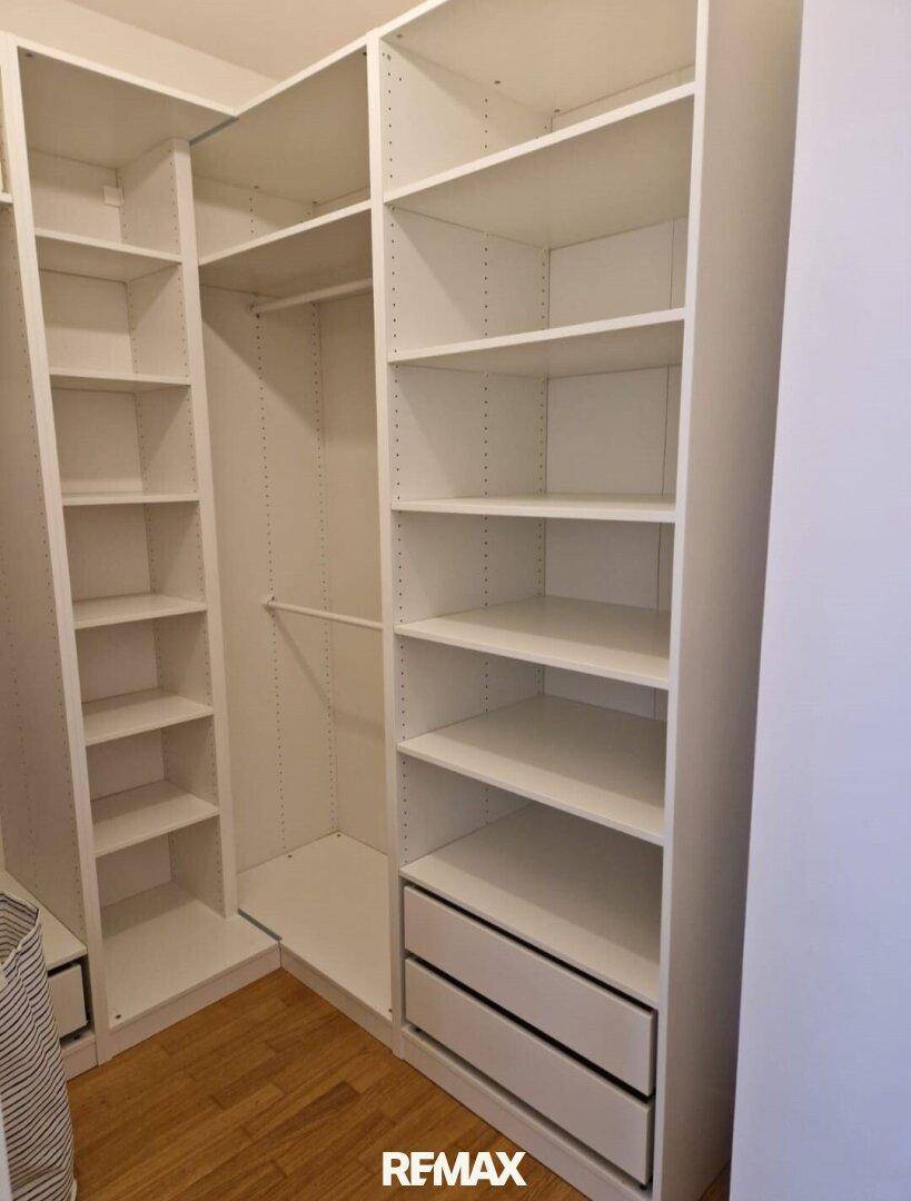 Praktischer begehbarer Kleiderschrank mit vielen Regalen und Schubladen für optimale Organisation.