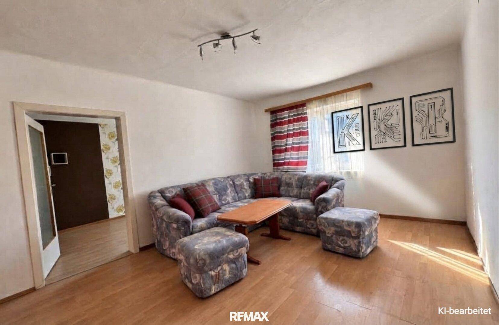Gemütliches Wohnzimmer mit gemustertem Ecksofa, Holztisch und Laminatboden.