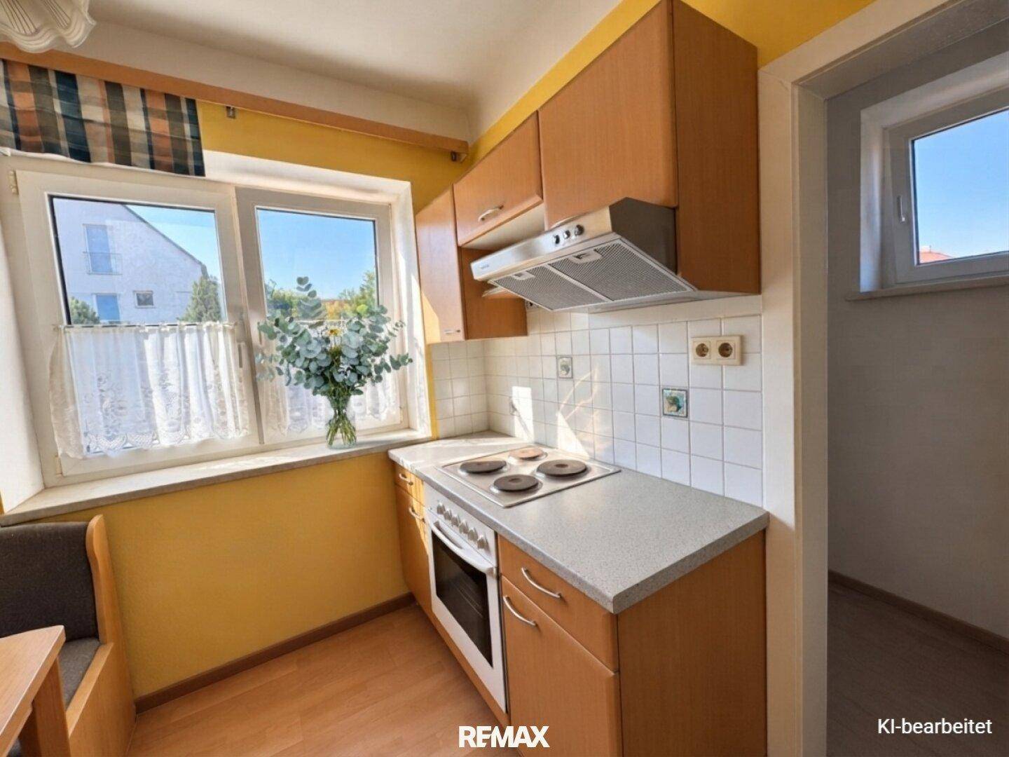 Kleine Küche mit Holzschränken, weiß gefliestem Spritzschutz und Fenster.