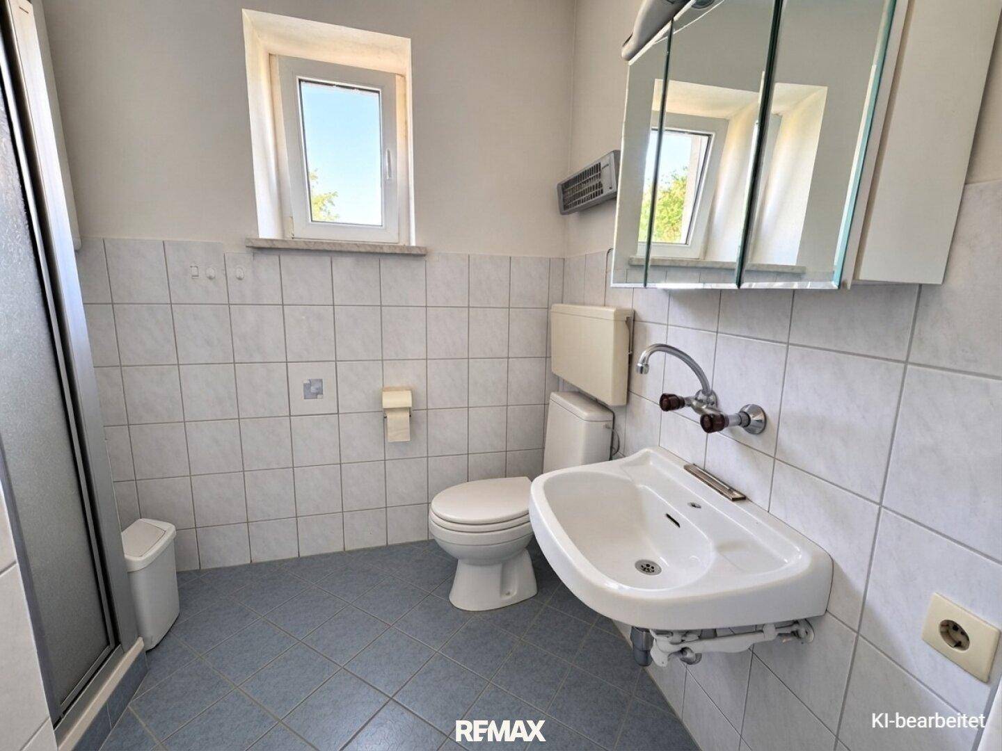 Badezimmer mit weißen und blauen Fliesen, WC, Waschbecken und Duschkabine.