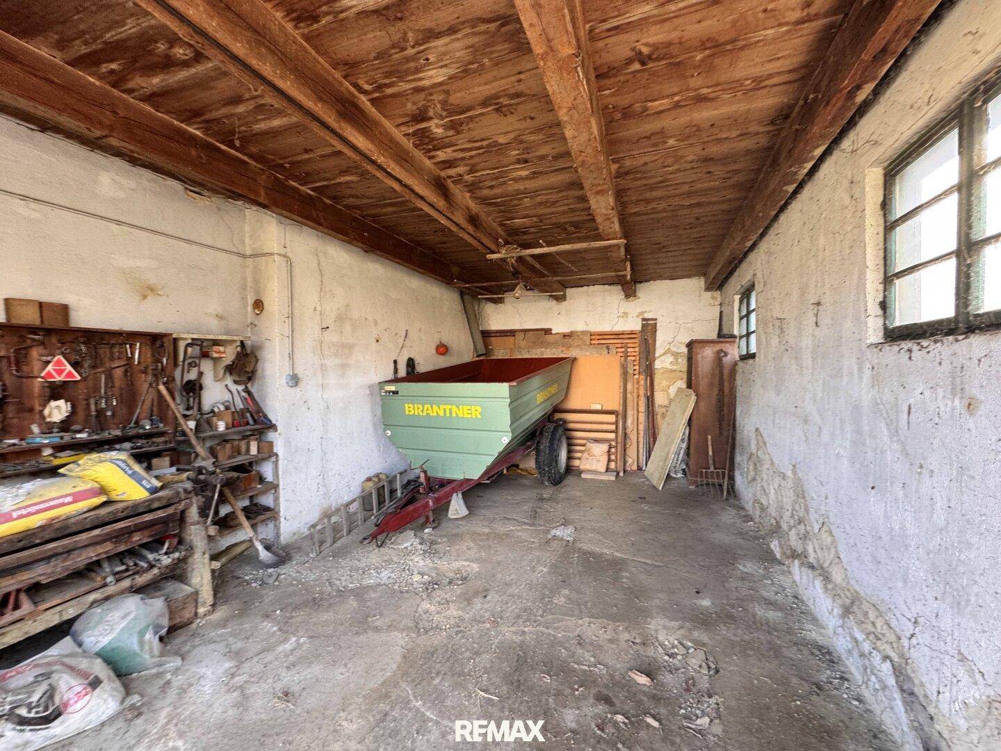 Geräumige Garage oder Werkstatt mit Holzbalken und Betonboden.
