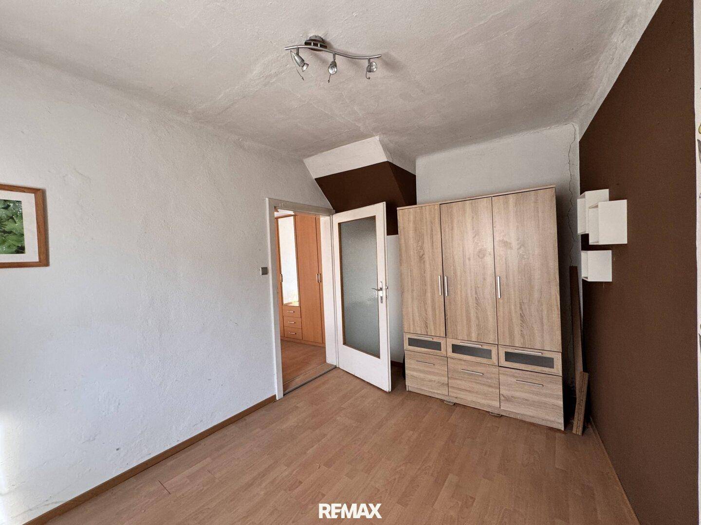 Schlafzimmer mit Laminatboden und großem Holzschrank.