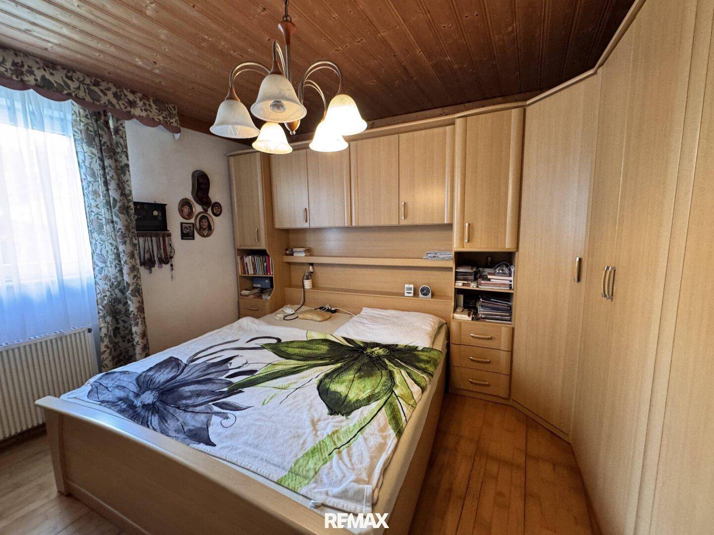 Schlafzimmer mit Einbauschränken aus Holz, Doppelbett und Holzdecke.
