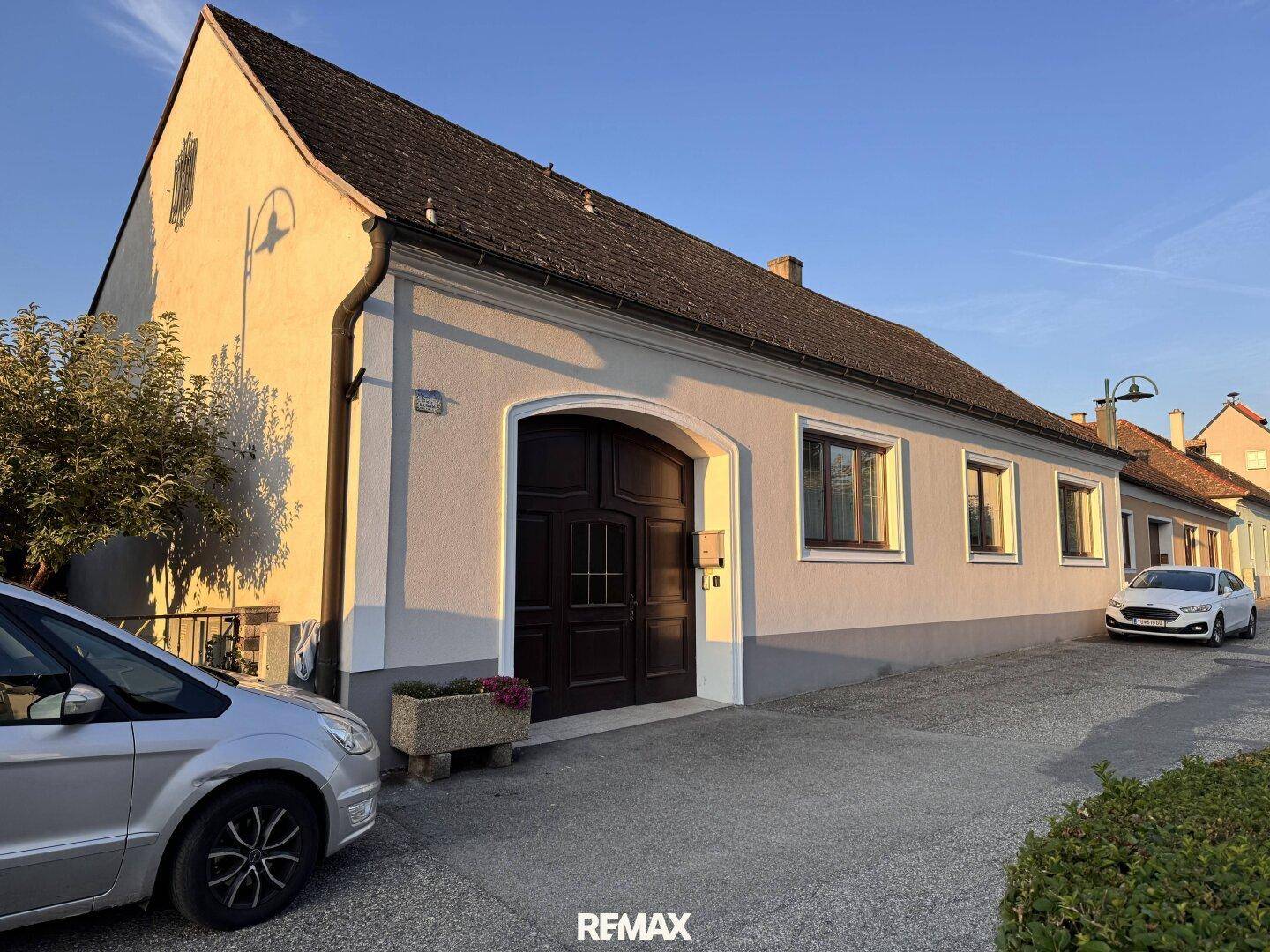 Vorderansicht des Hauses mit traditioneller Architektur und geparkten Fahrzeugen.