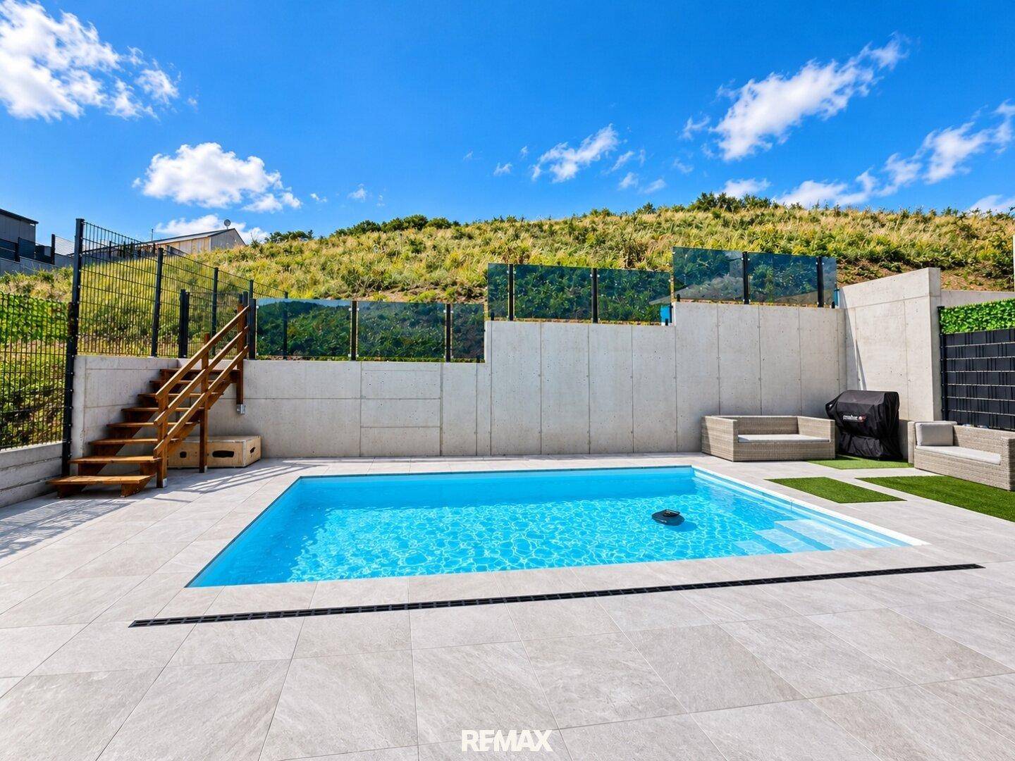 Außenbereich mit modernem Pool, gepflasterter Terrasse und Sitzgelegenheiten.