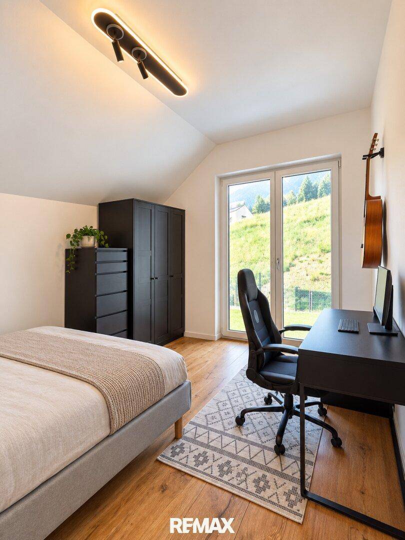 Schlafzimmer mit Holzboden, Schreibtisch und Fenster mit Blick ins Grüne.