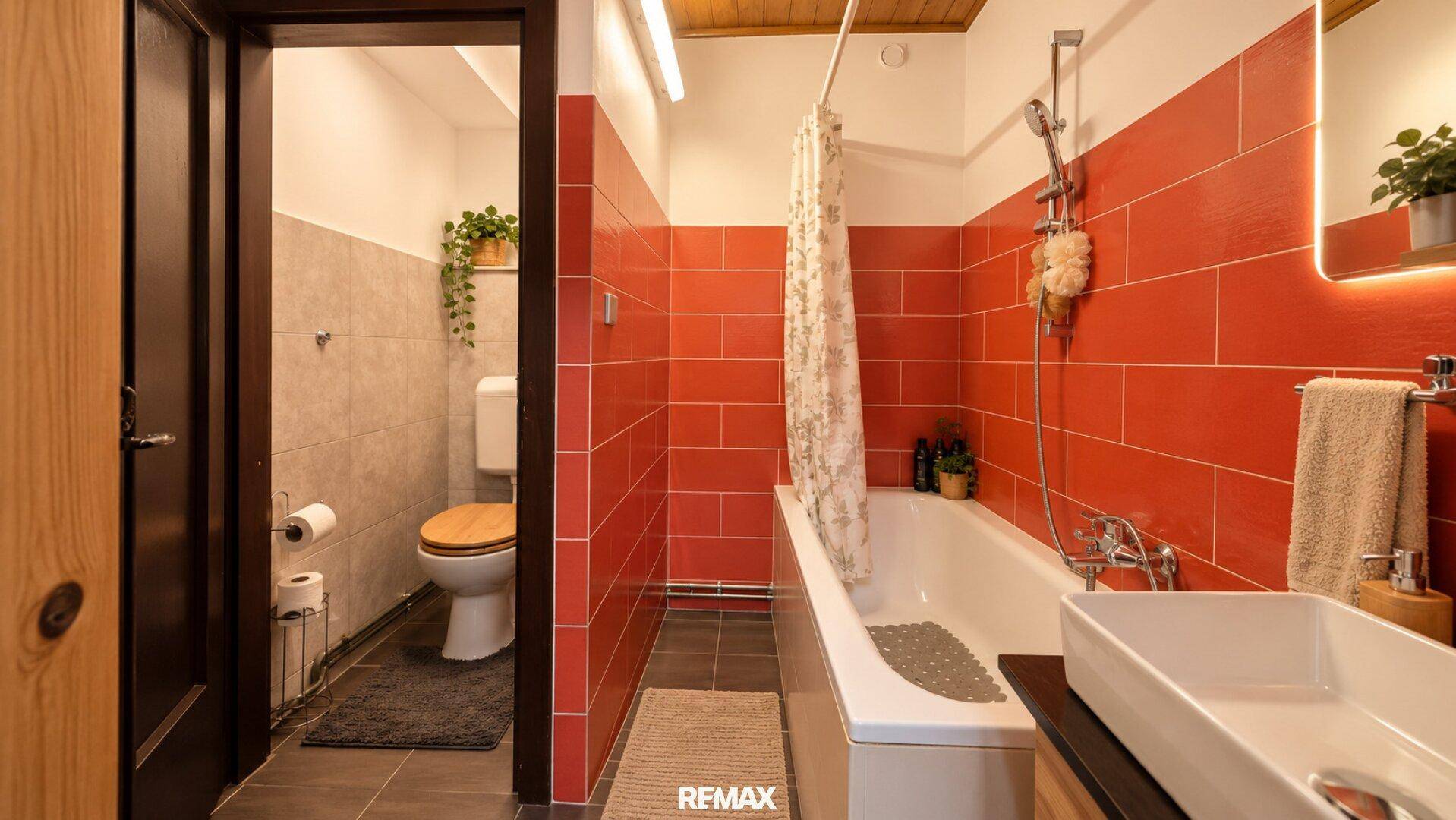 Badezimmer mit Badewanne, Dusche und auffälligen roten Fliesen, daneben ein separates WC.