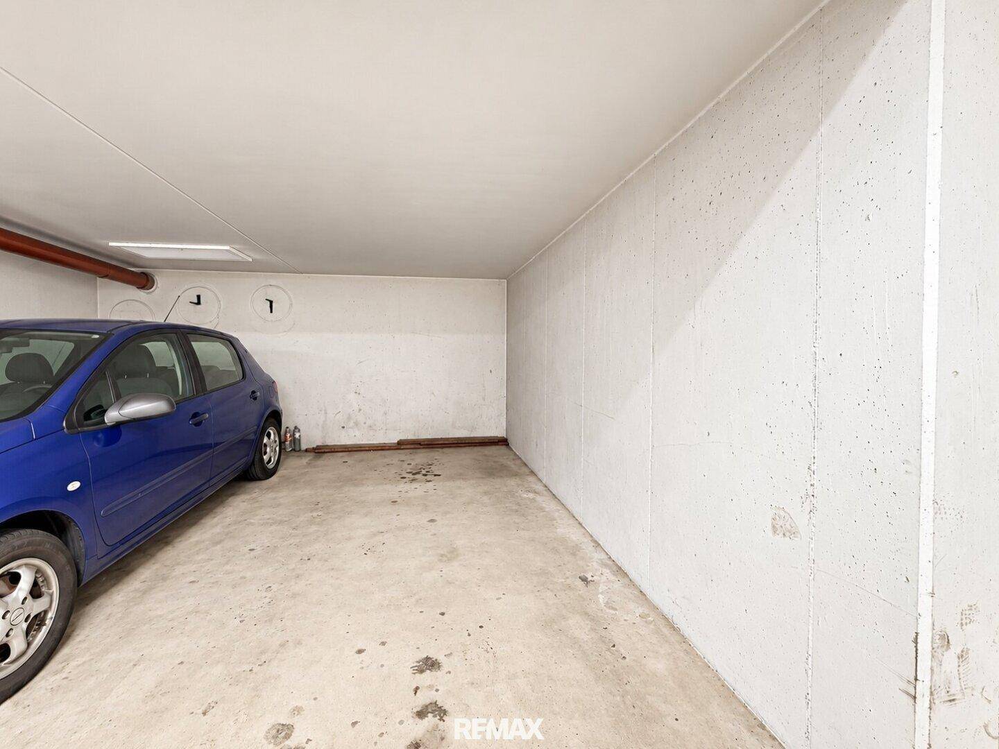 Einzelner Parkplatz in einer Tiefgarage mit Betonwänden und -boden.