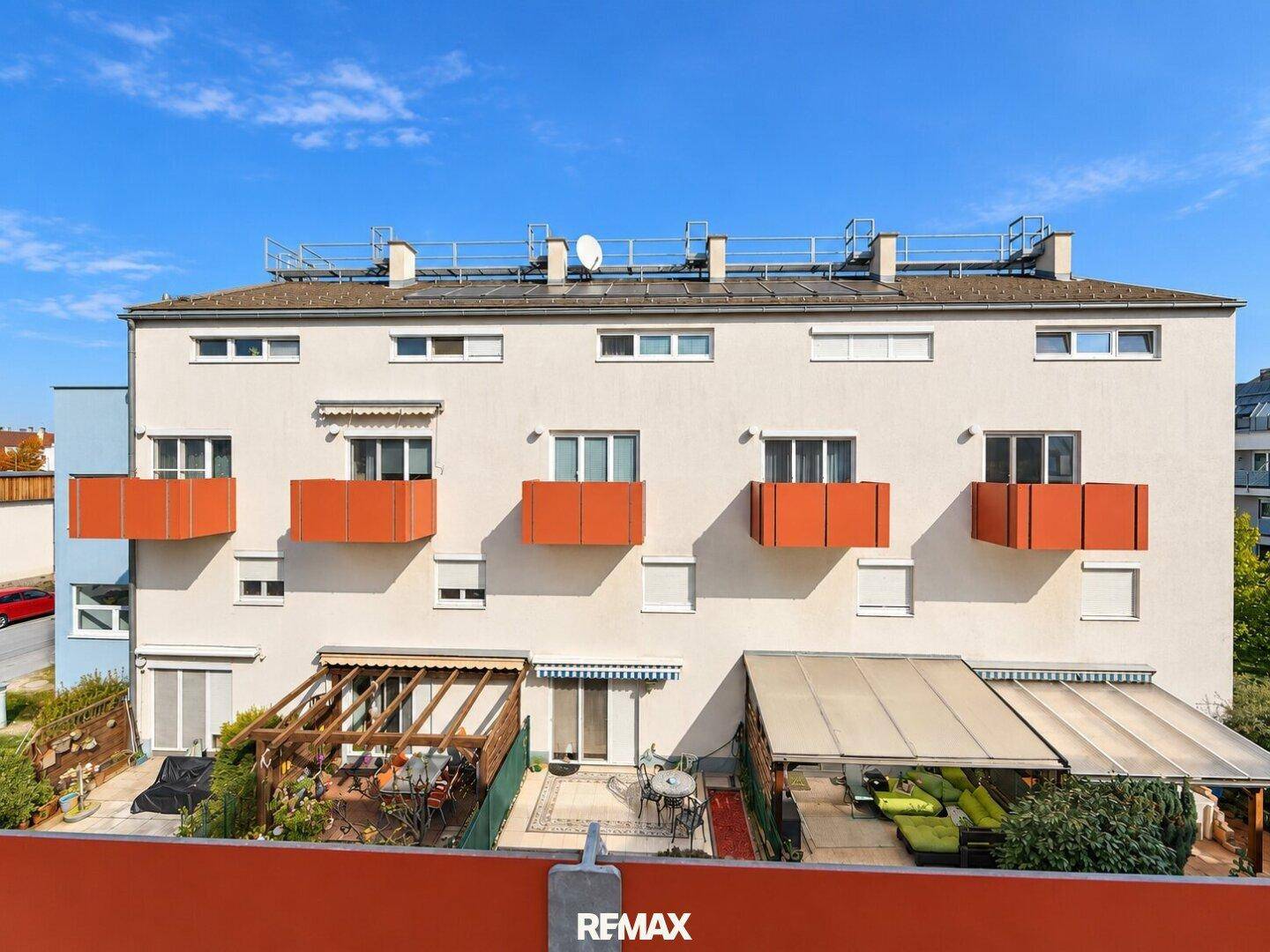 Fassade eines Wohngebäudes mit mehreren Balkonen und Terrassen im Erdgeschoss.