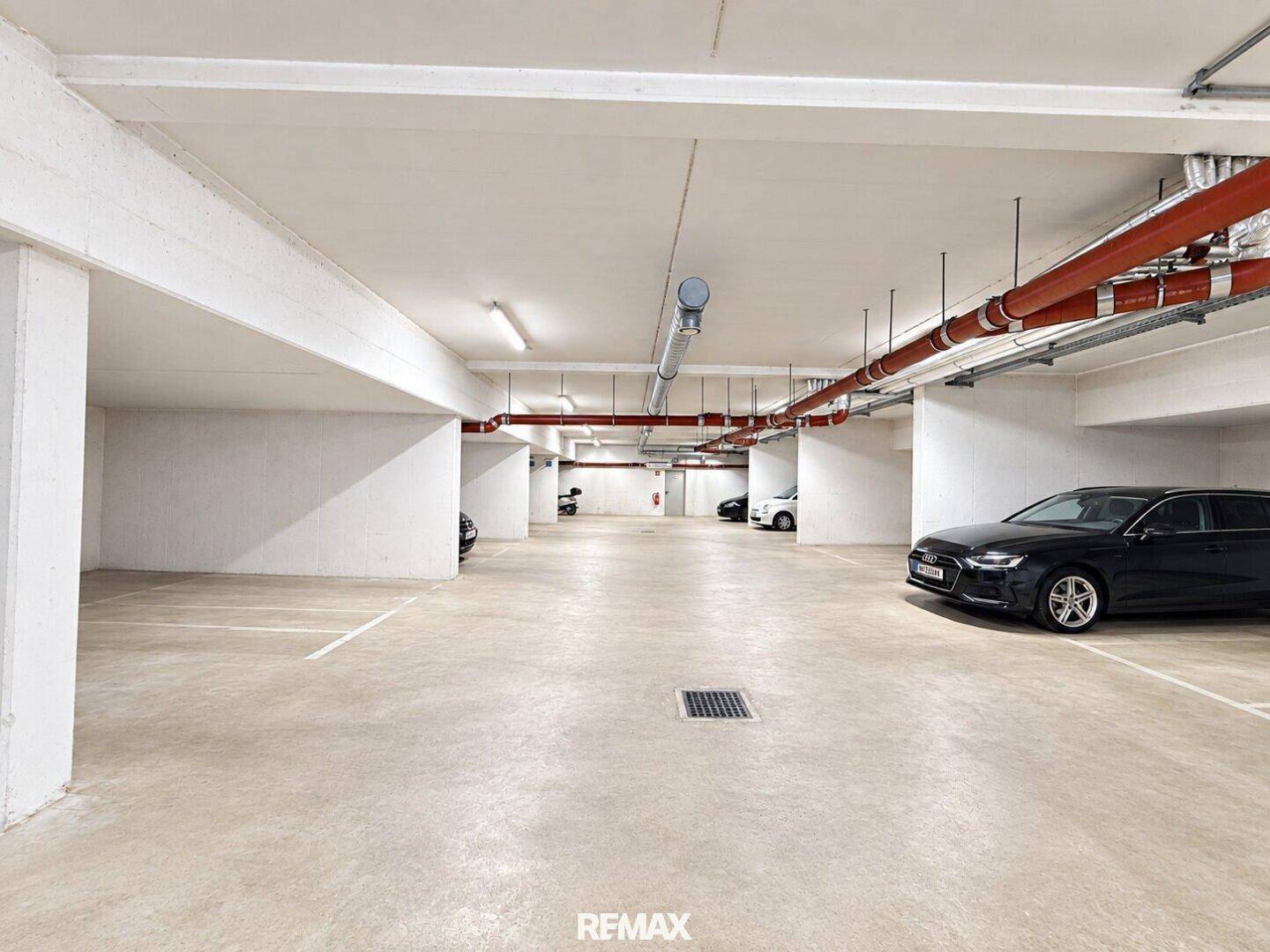 Geräumige Tiefgarage mit markierten Parkplätzen und geparkten Fahrzeugen.