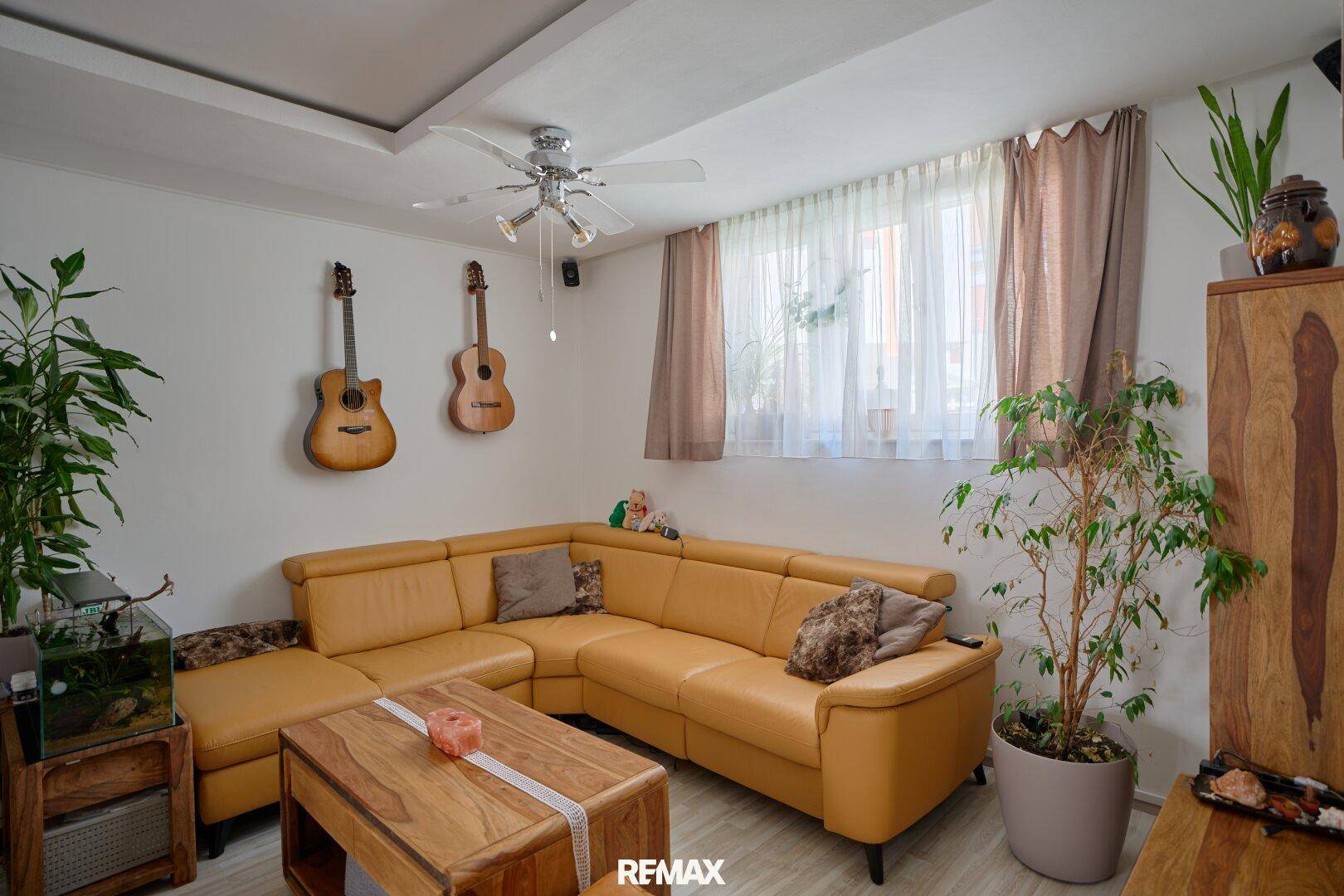 Gemütliches Wohnzimmer mit großer Eckcouch, Deckenventilator und Holztisch.