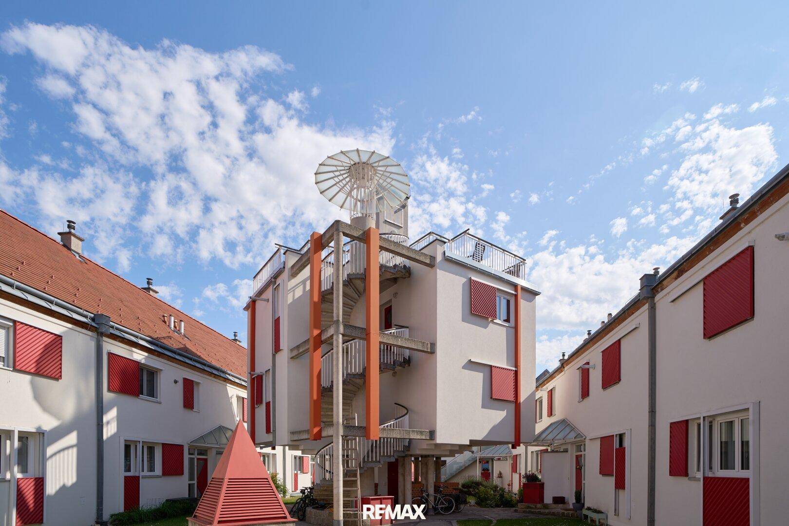Moderne Wohnanlage mit auffälliger Wendeltreppe und Dachterrasse.