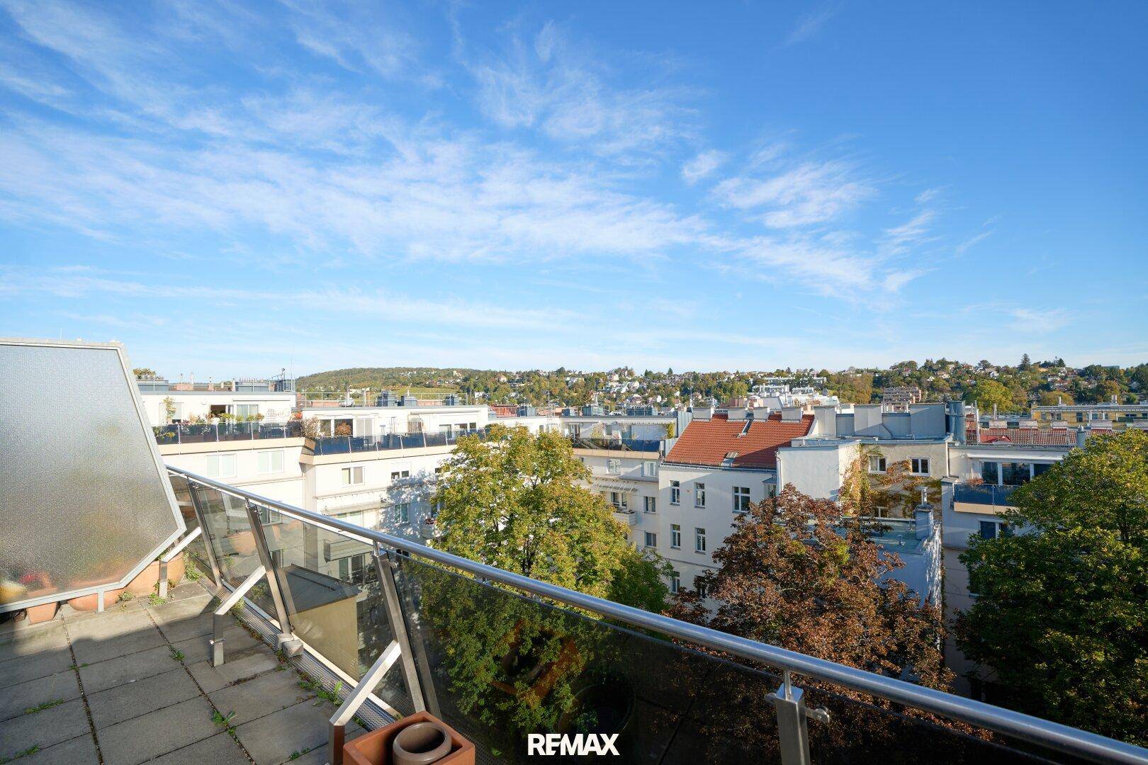 Geräumiger Balkon mit Fliesenboden und weitem Blick über die Stadt und grüne Hügel.