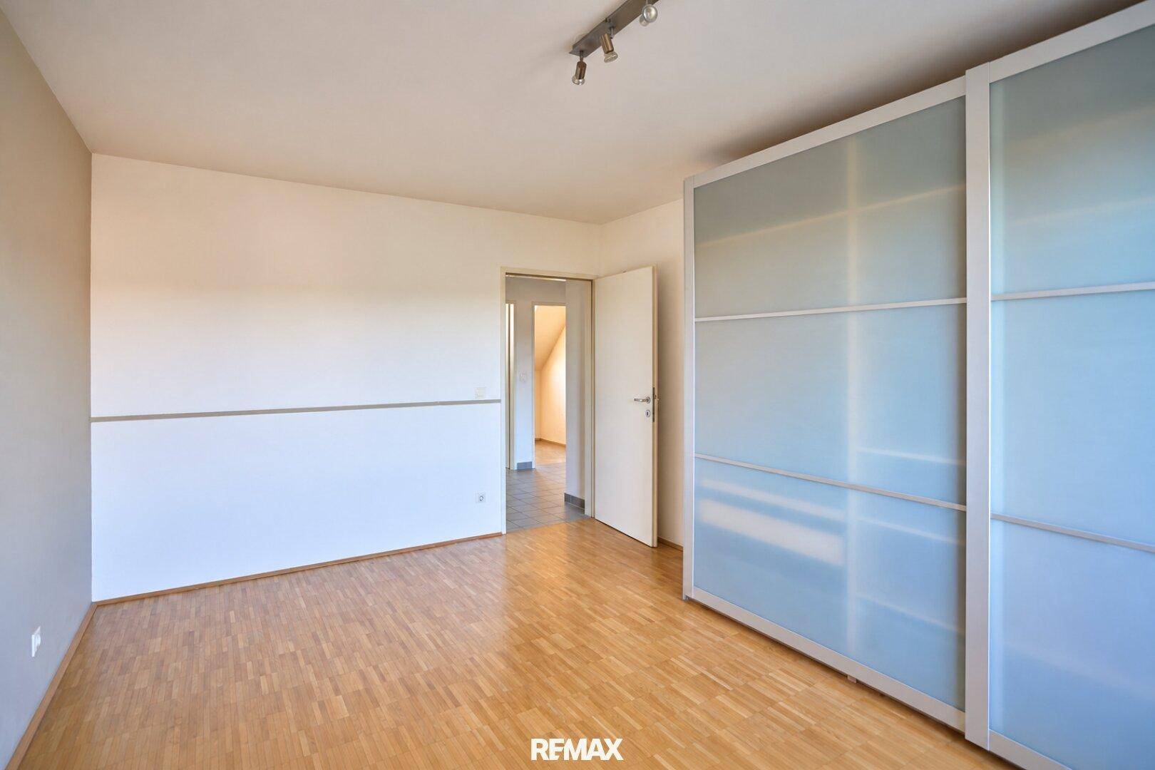 Schlafzimmer mit Parkettboden und großen Schiebetürenschränken.