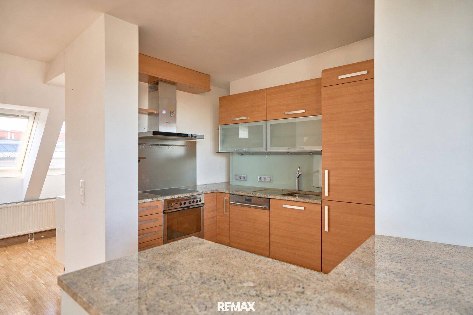 Funktionale Küche mit Holzschränken, Granitarbeitsplatte und integrierten Geräten.