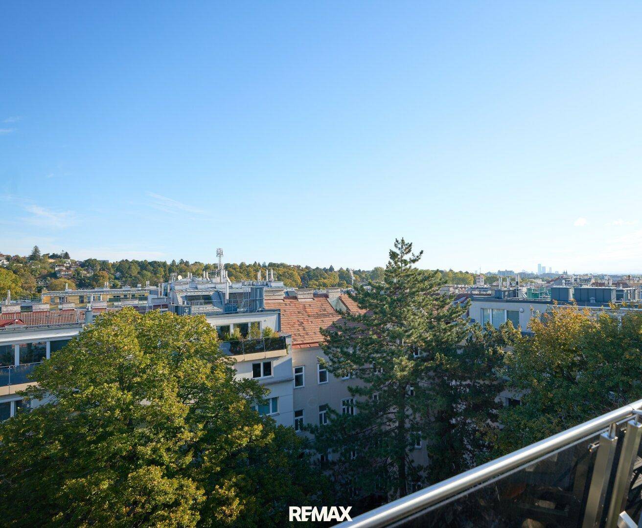 Panoramablick vom Balkon auf die Stadtlandschaft und die umliegenden Bäume.