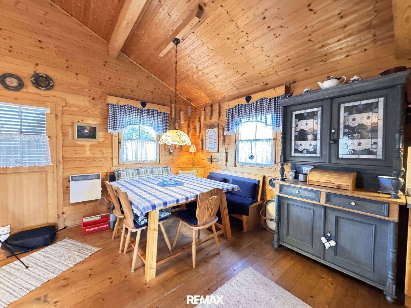 Gemütlicher Essbereich in einem Holzhaus mit traditionellen Möbeln und karierten Vorhängen.