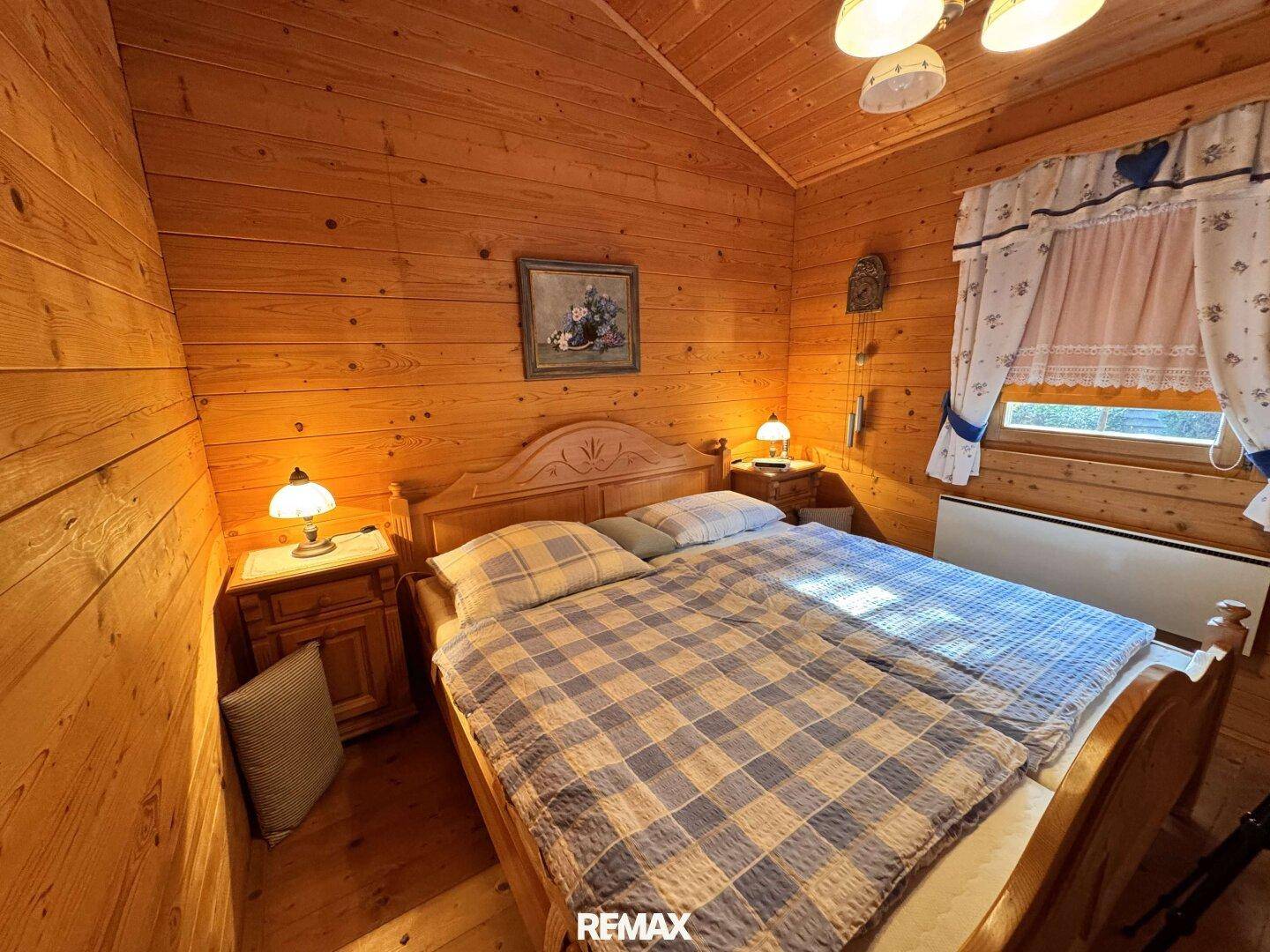Gemütliches Schlafzimmer mit Holzwänden, Holzboden und einem Doppelbett in traditionellem Stil.