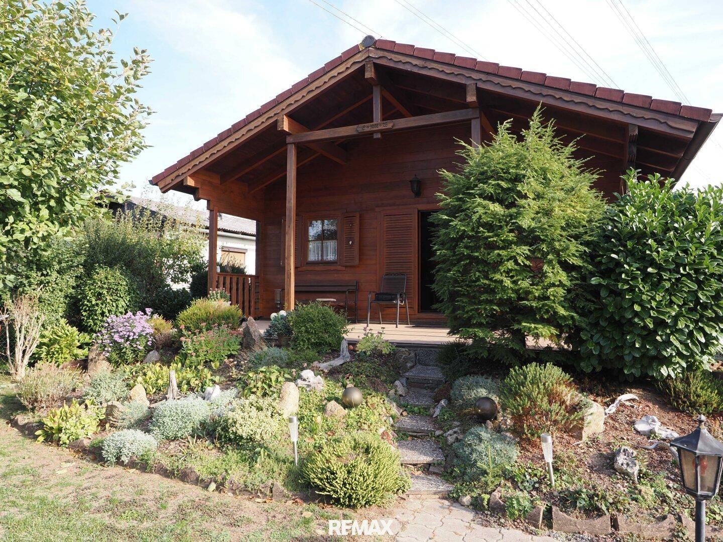 Charmantes Holzhaus mit überdachtem Eingangsbereich und einem liebevoll gestalteten Vorgarten.
