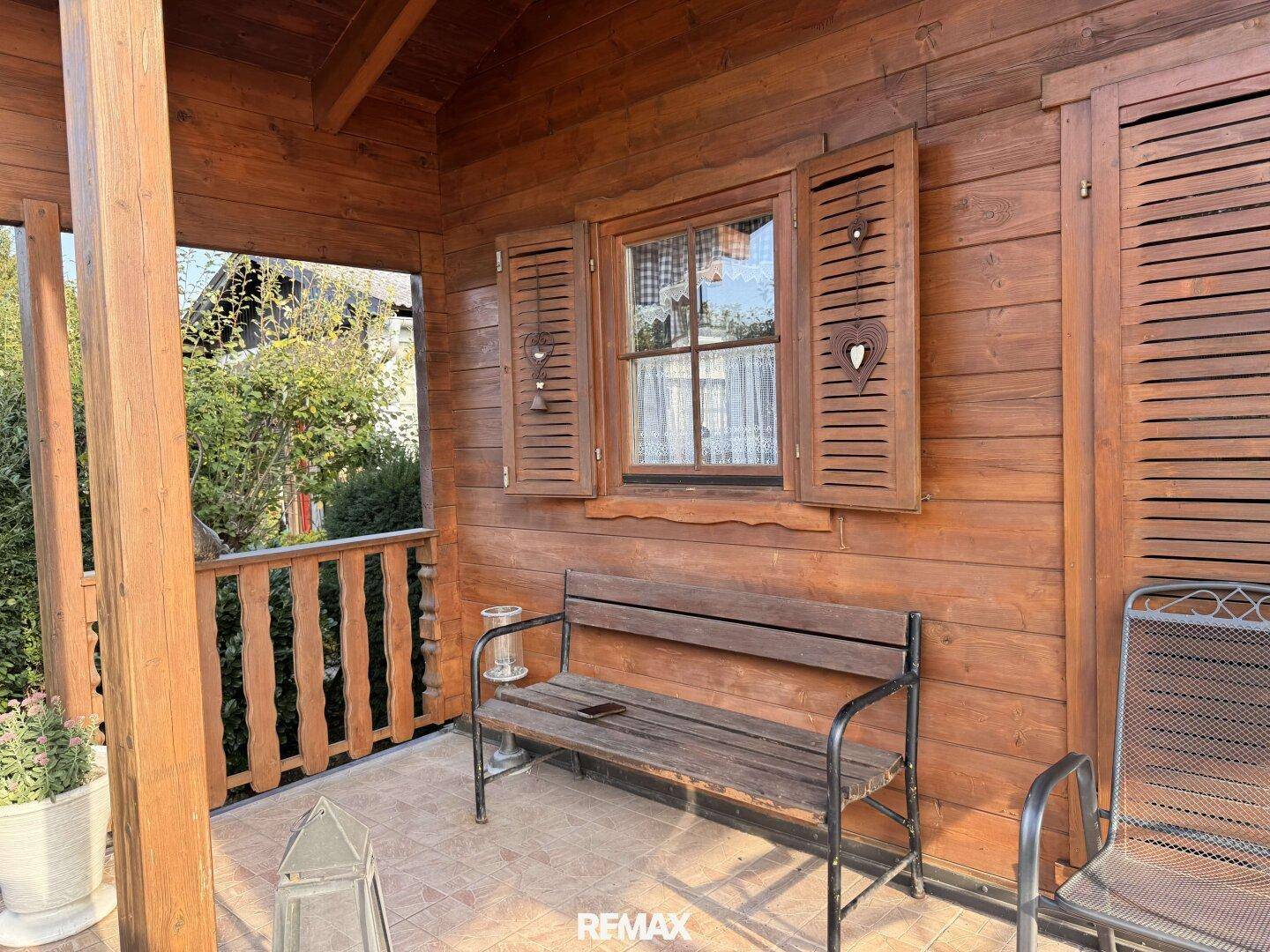 Überdachter Balkon mit Holzbank und Blick ins Grüne, perfekt zum Entspannen.