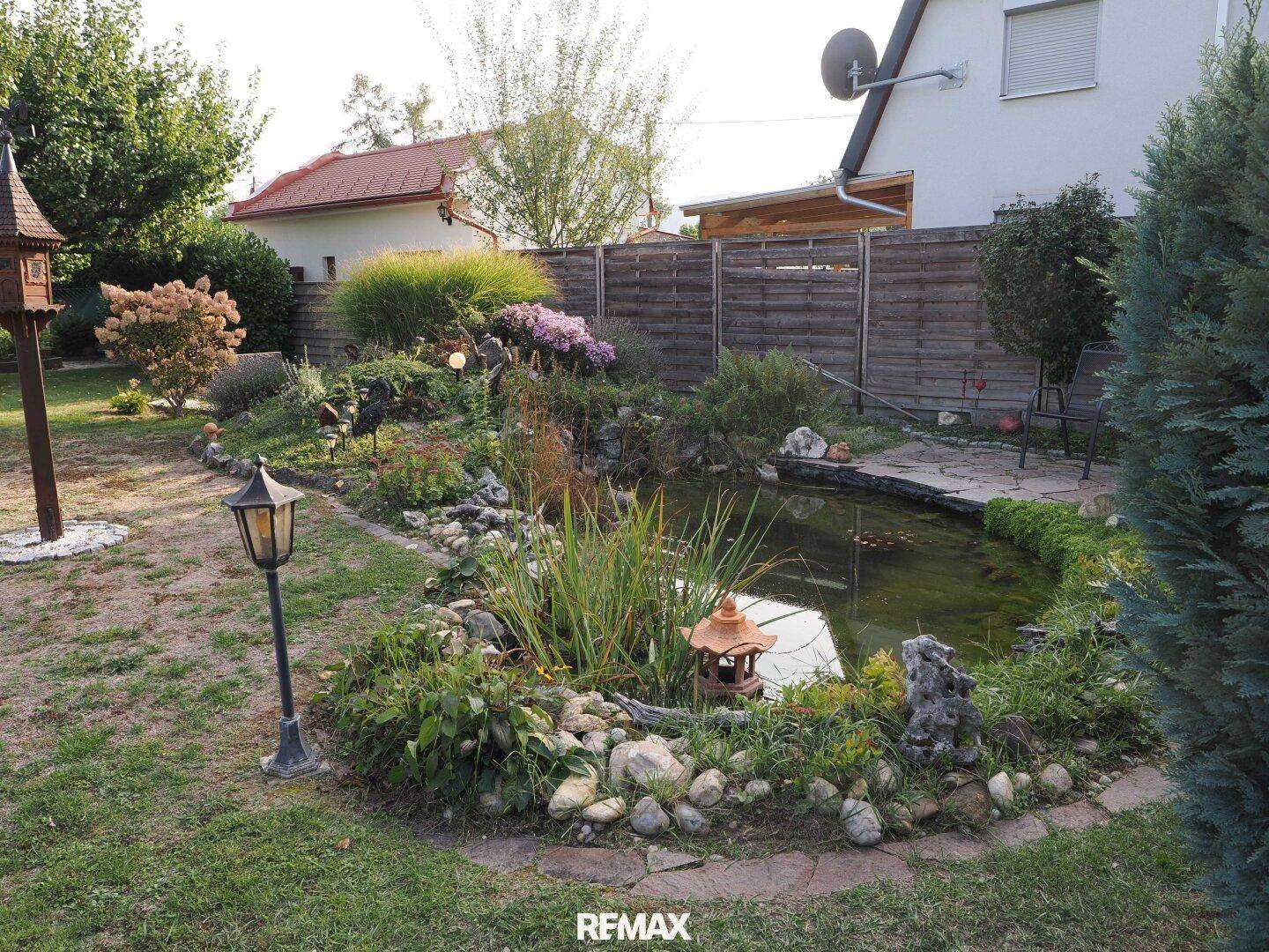 Gepflegter Gartenbereich mit einem dekorativen Teich und vielfältiger Bepflanzung.