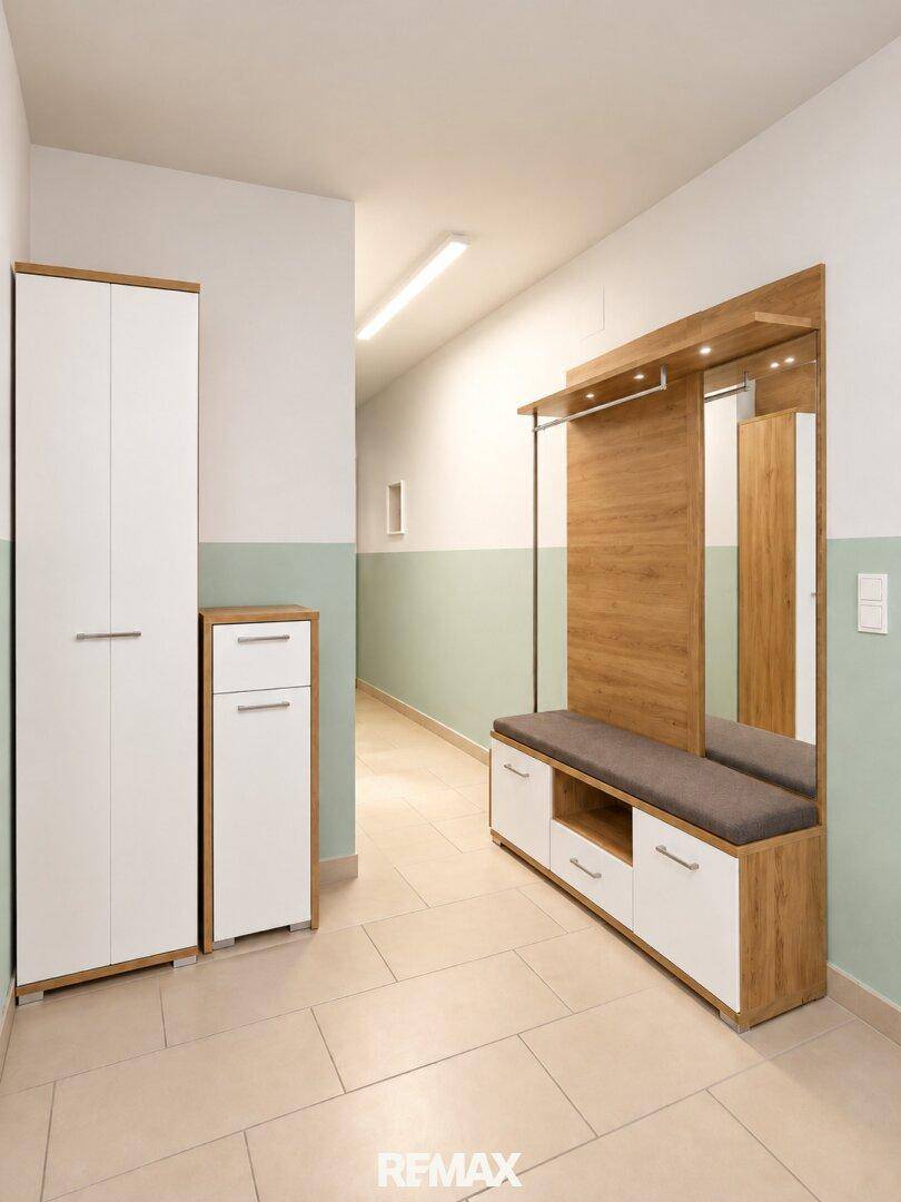 Eingangsbereich mit modernem Garderobenschrank, Spiegel und Sitzbank.